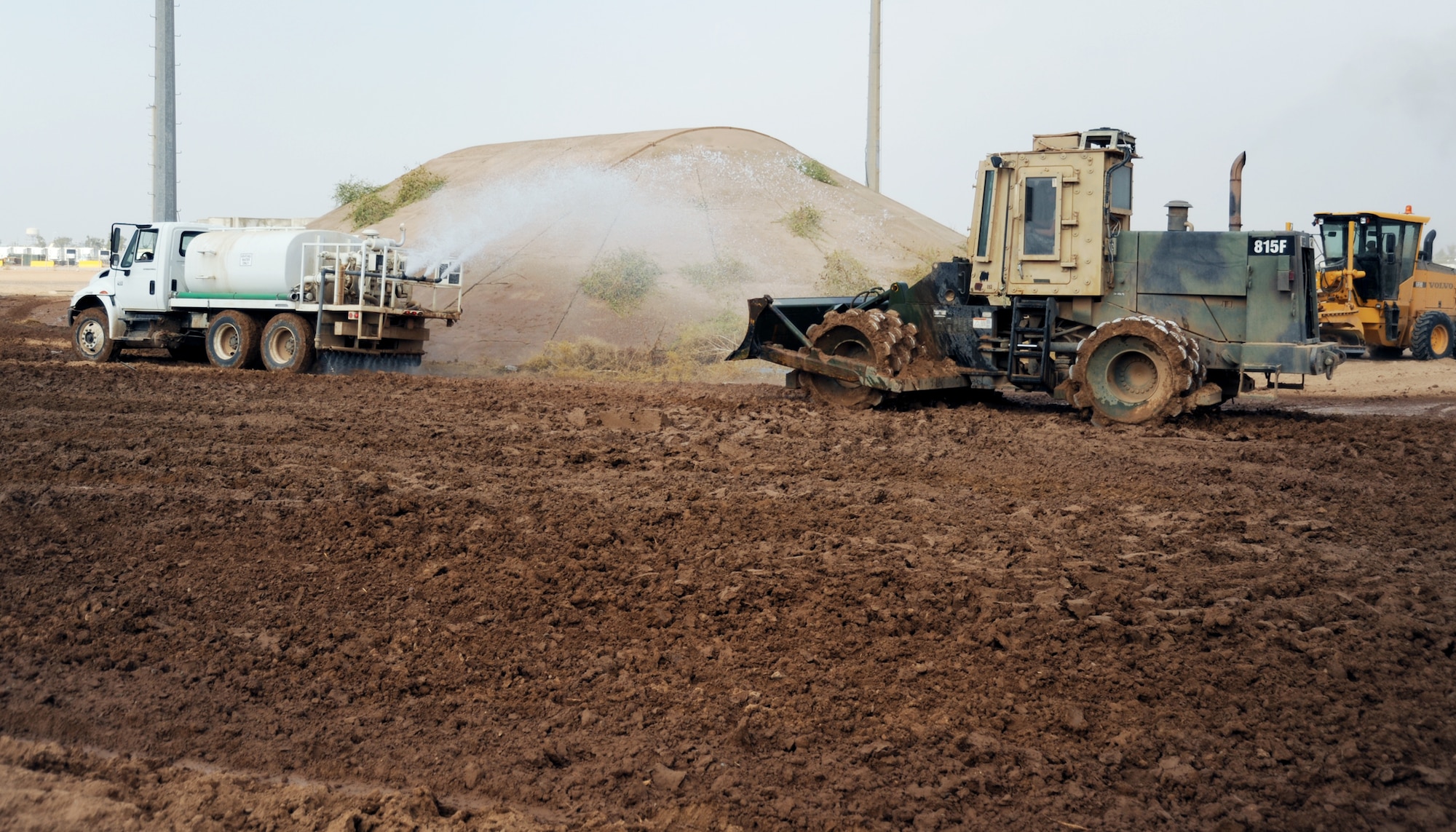 JOINT BASE BALAD, Iraq -- Airmen of the 732nd Expeditionary Civil Engineer Squadron use a 1500 gallon water truck to soften the earth for a sheep's foot roller, as it compacts the soil for a new container repair yard Nov. 2, 2009. By using containers repaired here instead of purchasing new ones, the projected savings total more than $100 million as military assets withdraw from Iraq. (U.S. Air Force photo/Senior Airman Christopher Hubenthal)
