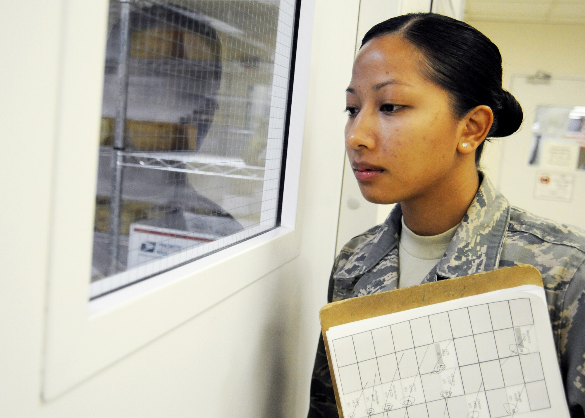 JOINT BASE BALAD, Iraq -- Senior Airman Faith Lumabao, 332nd Expeditionary Medical Support Squadron patient valuables and bed status technician, checks on patients in a waiting room at the Air Force Theater Hospital Nov. 2, 2009. Airman Lumabao created a patient tracking system which provides accountability information for the entire hospital. (U.S. Air Force photo/Senior Airman Christopher Hubenthal)