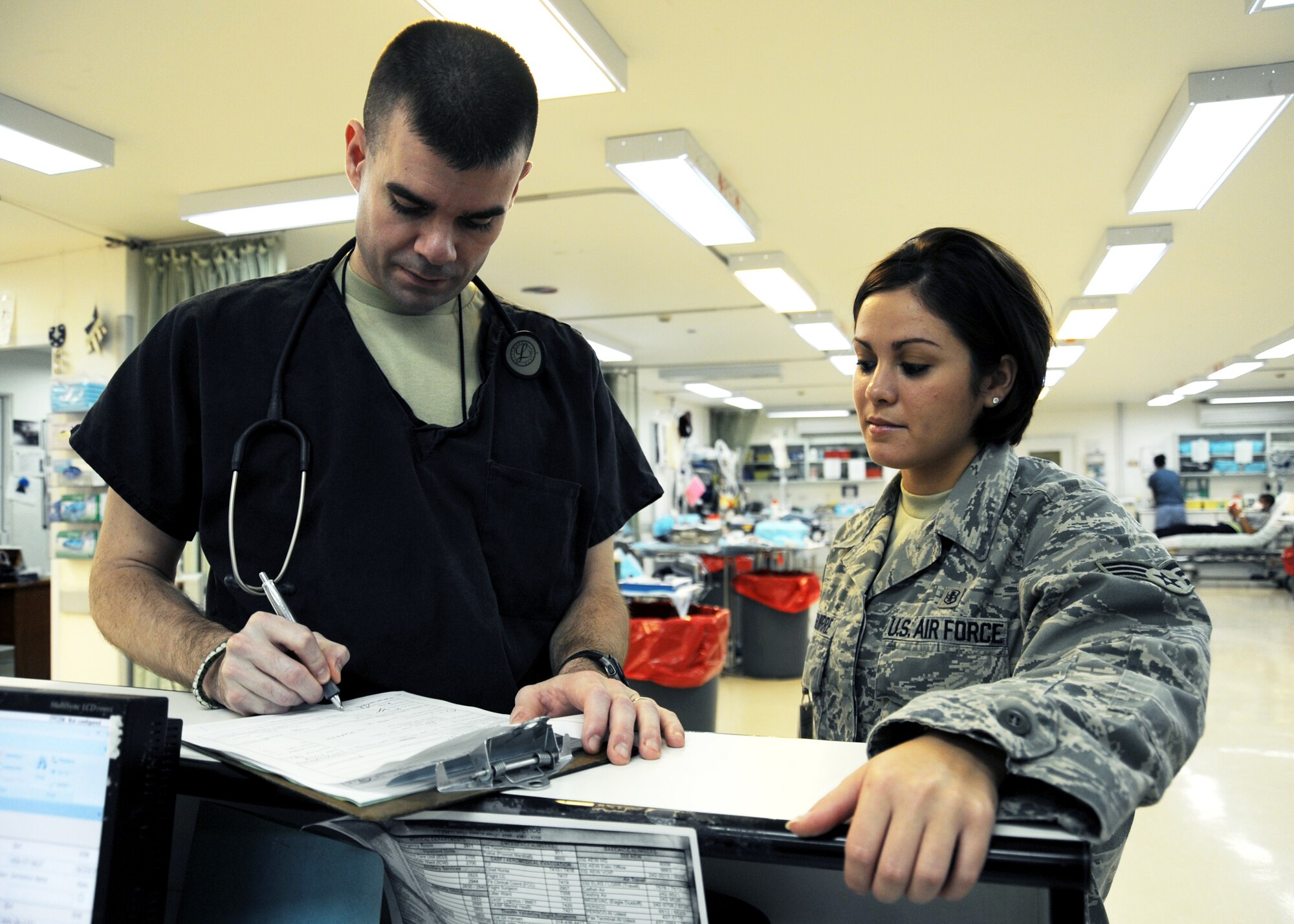 JOINT BASE BALAD, Iraq -- Maj. Shanon Madrid and Senior Airman Catherine Izaguirre, both from the 332nd Expeditionary Medical Support Squadron, fill out necessary paperwork for tracking patient information at the Air Force Theater Hospital Nov. 2, 2009. Airman Izaguirre is responsible for documenting patient information, including known injuries and unit information. (U.S. Air Force photo/Senior Airman Christopher Hubenthal)