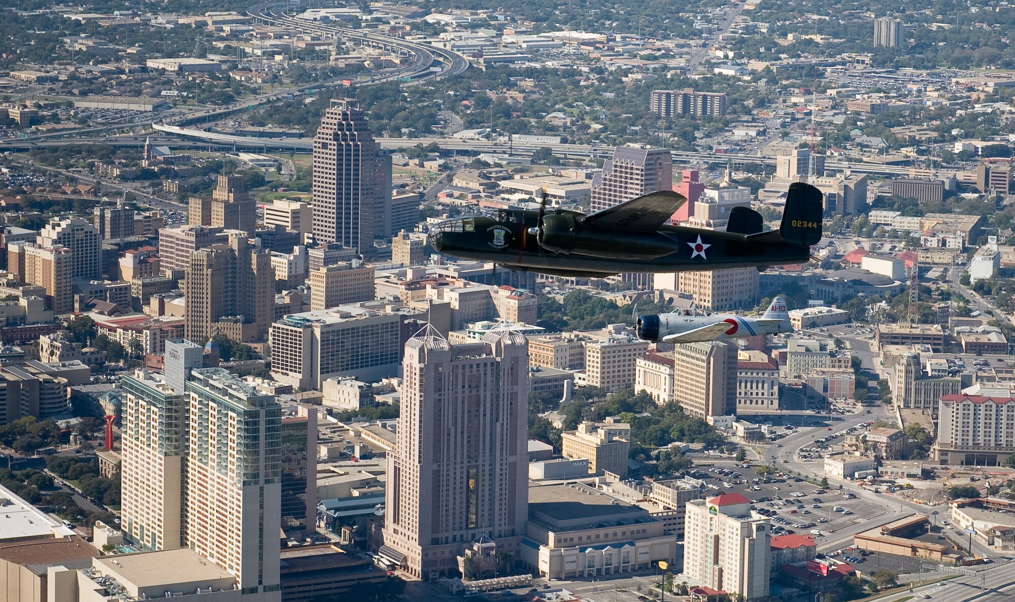The B-25 Mitchell medium bomber "Special Delivery" and a Japanese A6M2 Zero replica built from a North American T-6 Texan fly over downtown San Antonio Nov. 5, 2009.  The Alamo is visible in the stand of trees to the left and below the Zero.  Larry Gregory is one of the pilots of the B-25 from the Lone Star Flight Museum and Jim Ryan pilots the Zero of Tora Tora Tora.  The Disabled American Veterans Flight Team organized flights aboard historic and experimental air show aircraft for wounded warriors from the Warrior Transition Unit of the San Antonio Military Medical Center at Fort Sam Houston, Texas, two days before the Randolph Air Force Base "Forging the Future" Air Show.  (U.S. Air Force photo/Lance Cheung)