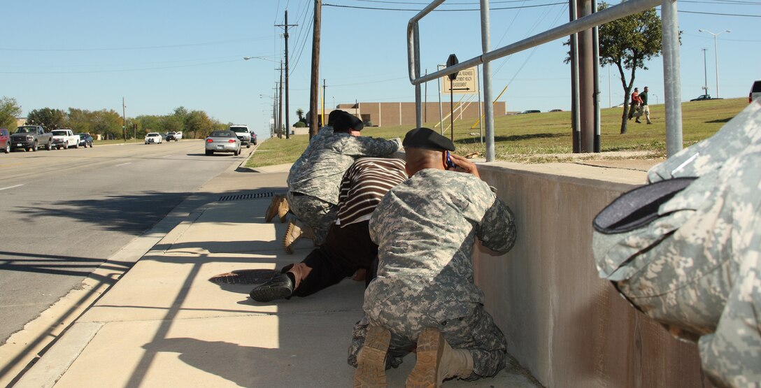 Bystanders crouch for cover as shots rang out from Fort Hood's Soldier Readiness Processing Center Nov. 5, 2009, as law enforcement officers run toward the sound of the gun.  A lone gunman killed 13 people and wounded 30 more in the incident.