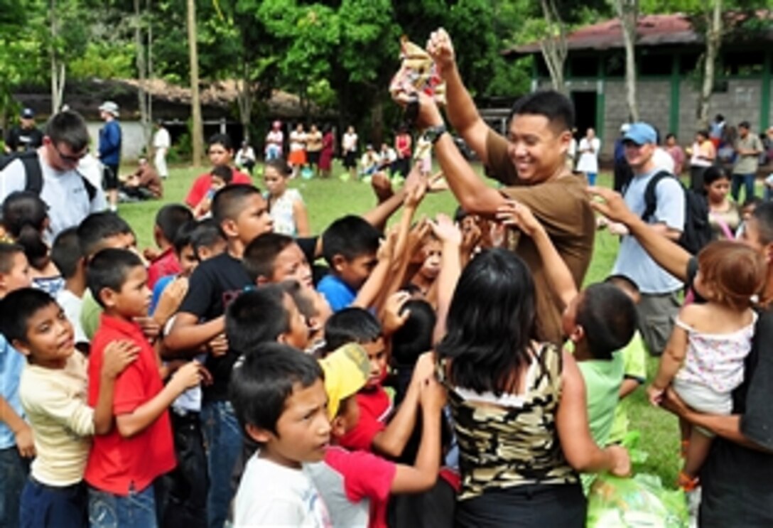 U.S. Air Force Staff Sgt. Song Moon hands out candy to a group of eager children in El Ciruelo, a mountain village near Comayagua, Honduras, Oct. 31, 2009. Eighty-one volunteers from Joint Task Force Bravo, which is under U.S. Southern Command, hiked more than five miles along a mountain road to deliver food to the remote village. Volunteers carried 122 bags of food, equaling 2,684 pounds.