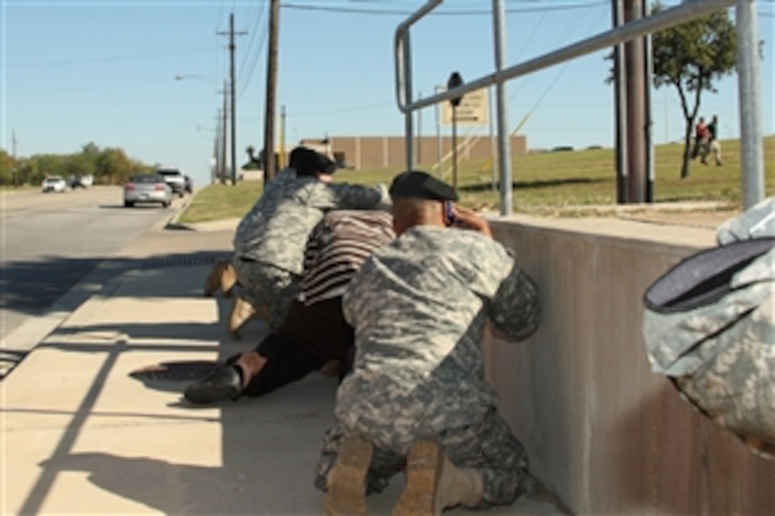 Bystanders crouch for cover as shots rang out from Soldier Readiness Processing Center on Fort Hood, Texas, Nov. 5, 2009, as law enforcement officers run toward the sound of the gun.  A lone gunman killed 13 people and wounded 30 more in the incident.