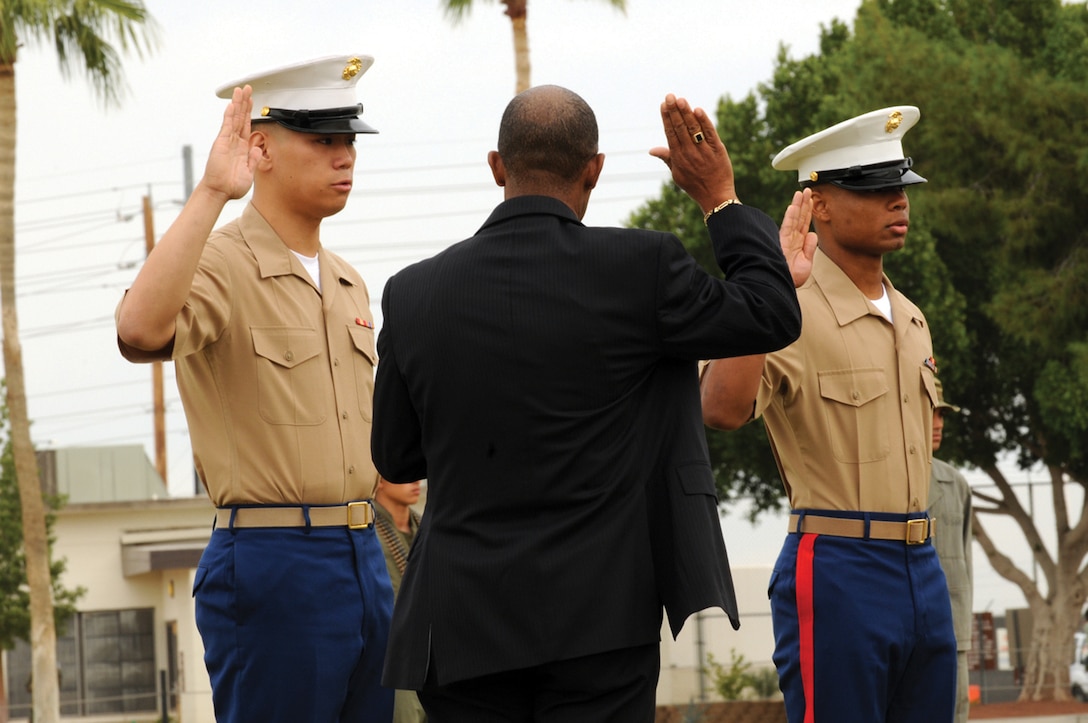 Lance Cpl. Hong Chen, left, Marine Attack Squadron 311 AV-8B Harrier mechanic, and Cpl. Josbie Morris, VMA-211 Harrier electrician, are sworn in by retired Master Gunnery Sgt. Leander B. Holston, U.S. citizenship and immigration services officer at the Marine Corps Air Station in Yuma, Ariz., during the station's birthday celebration, Nov. 6, 2009. Chen received a certificate of naturalization and Morris a certificate of citizenship after taking the oath of allegiance.
