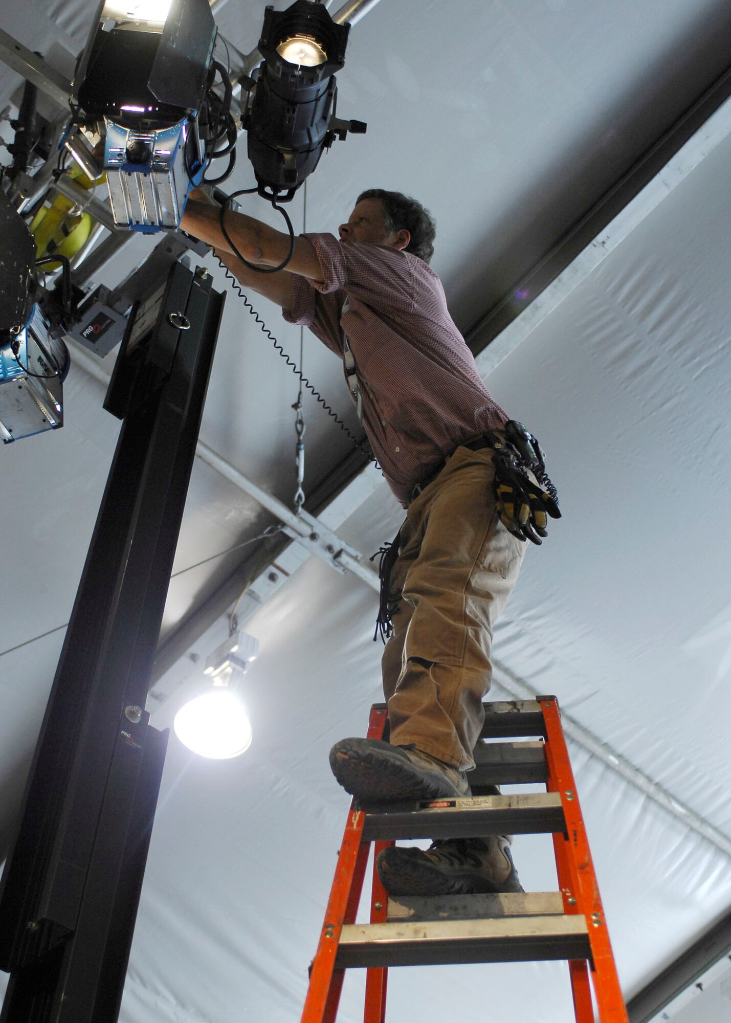 BAGRAM AIR FIELD, Afghanistan -- Dirk DeLaCour, an electrician for Fox Sports, adjusts the lights during set up Nov. 6, 2009.  The Fox Sports members transformed the MWR clamshell into a set for the "Fox NFL Sunday" team.  The "Fox NFL Sunday" team is scheduled to broadcast live Nov. 8, 2009 from here.  Mr. DeLaCour hails from Brooklyn, N.Y.  (U.S. Air Force photo/Senior Airman Felicia Juenke)