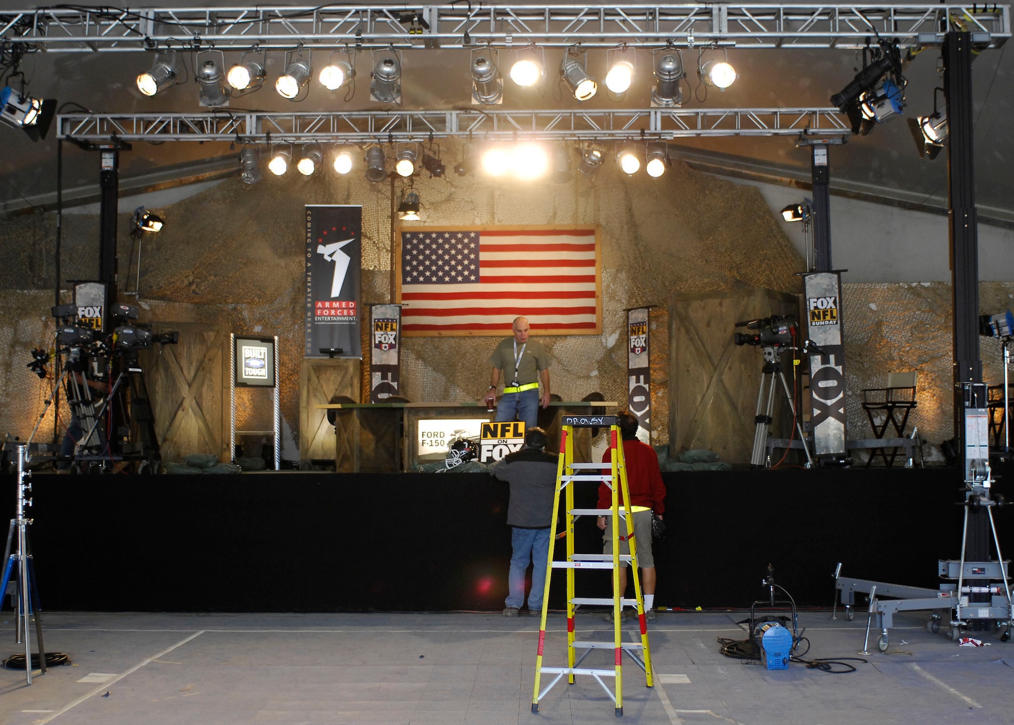 BAGRAM AIR FIELD, Afghanistan -- Stage crew members transform the MWR clamshell into a set for the "Fox NFL Sunday" team Nov. 6, 2009.  Bagram welcomed Jay Glazer, Howie Long, Terry Bradshaw, Michael Strahan, Jimmy Johnson, and Curt Menefee.  The "Fox NFL Sunday" team is scheduled to broadcast live Nov. 8, 2009 from here.  (U.S. Air Force photo/Senior Airman Felicia Juenke)