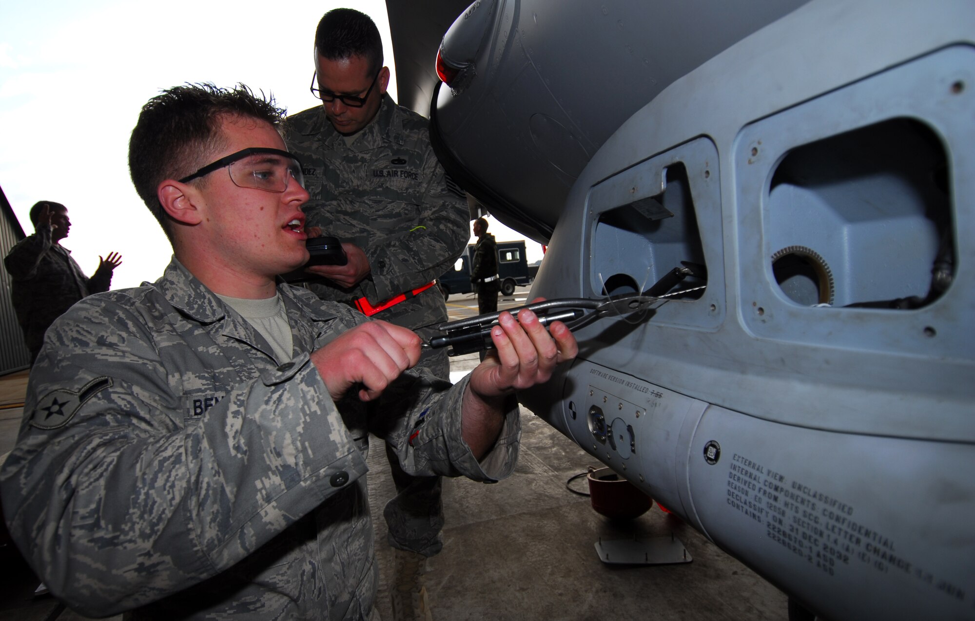 MISAWA AIR BASE, Japan--Airman Nickolas Bennett, 14th Aircraft Maintenance Unit avionics technician, installs safety wire on a high speed anti-radiation missile pod while being inspected by Tech. Sgt. Rex Hernandez, 35th Maintenance Group quality assurance inspector, Nov. 6, in a 14th AMU hardened aircraft shelter. Airman Bennett passed his quality verification inspection earning him kudos in the specialist flight. (U.S. Air Force Photo/Staff Sgt. Phillip Butterfield)