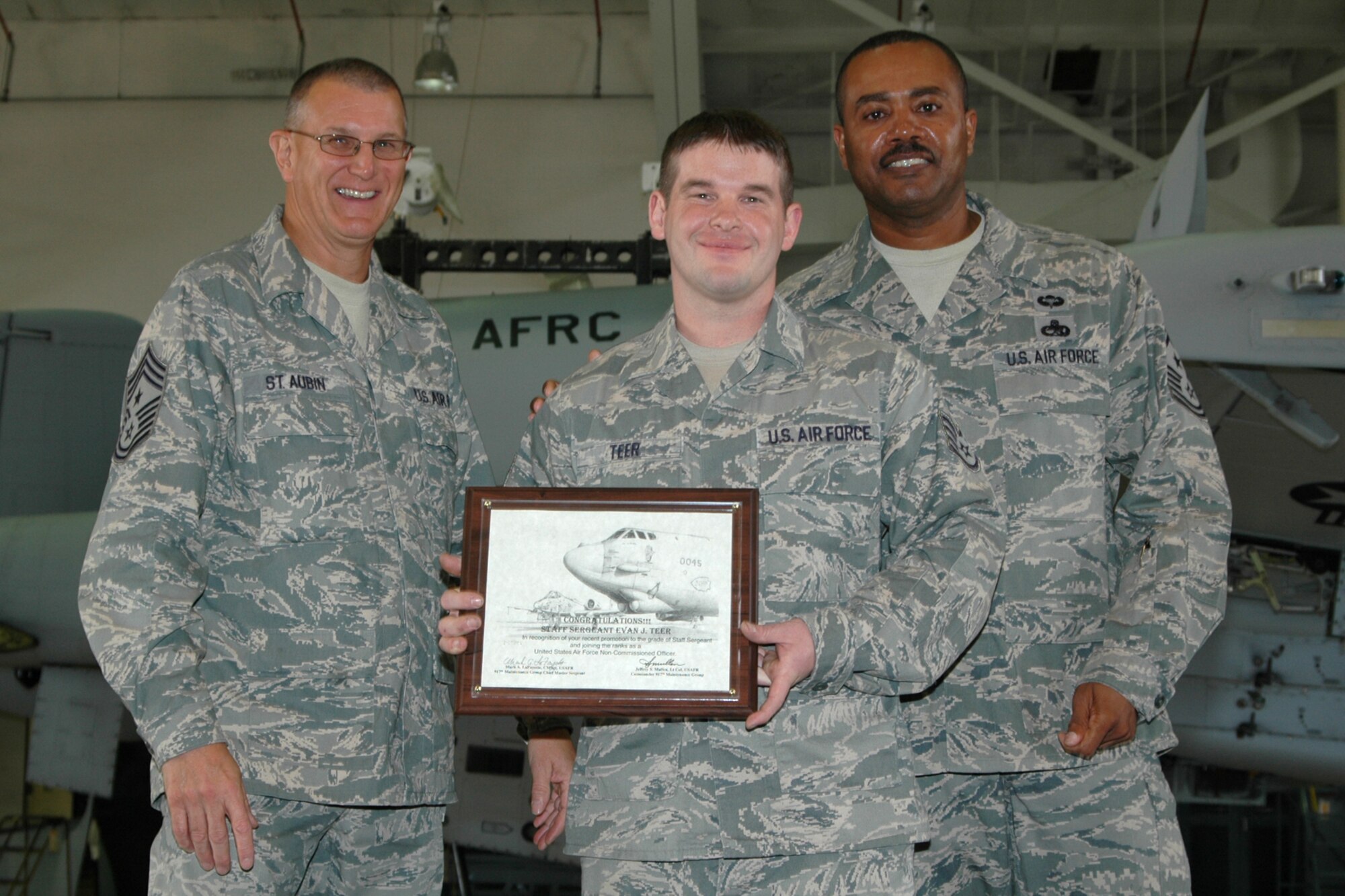 Staff Sgt. Evan Teer, jet engine mechanic, 917th Maintenance Group, a newly promoted Non-commissioned Officer, grins as he accepts his certificate during the group’s NCO induction ceremony at Barksdale Air Force Base, La., November 7, 2009.  Presenting the certificate were Chief Master Sgt. Lesley Morrissette, 10th Air Force, command chief and Chief Master Sgt. Keith St. Aubin, 917th Wing, command chief.  Twenty-one staff sergeants were recognized for their promotions. (U.S. Air Force photo/Senior Airman Crystal Jordan)