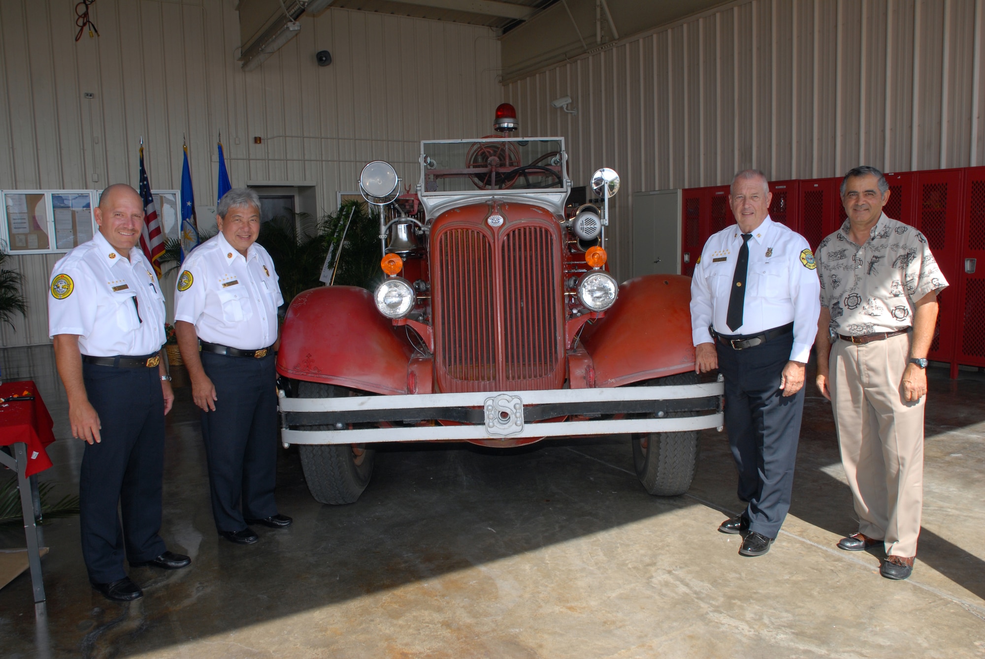 HICKAM AIR FORCE BASE, Hawaii -- Chief's Kenneth Silva and Alvin Tomita, Honolulu Fire Department, Chief William Moore, Hickam Fire Department, and HFD retired Chief Attilio Leonardi, pose for a group photo with a retired Hickam fire truck during the Hickam Fire Department's 70th Anniversary celebration Nov. 6. (U.S. Air Force photo/Senior Airman Gustavo Gonzalez)