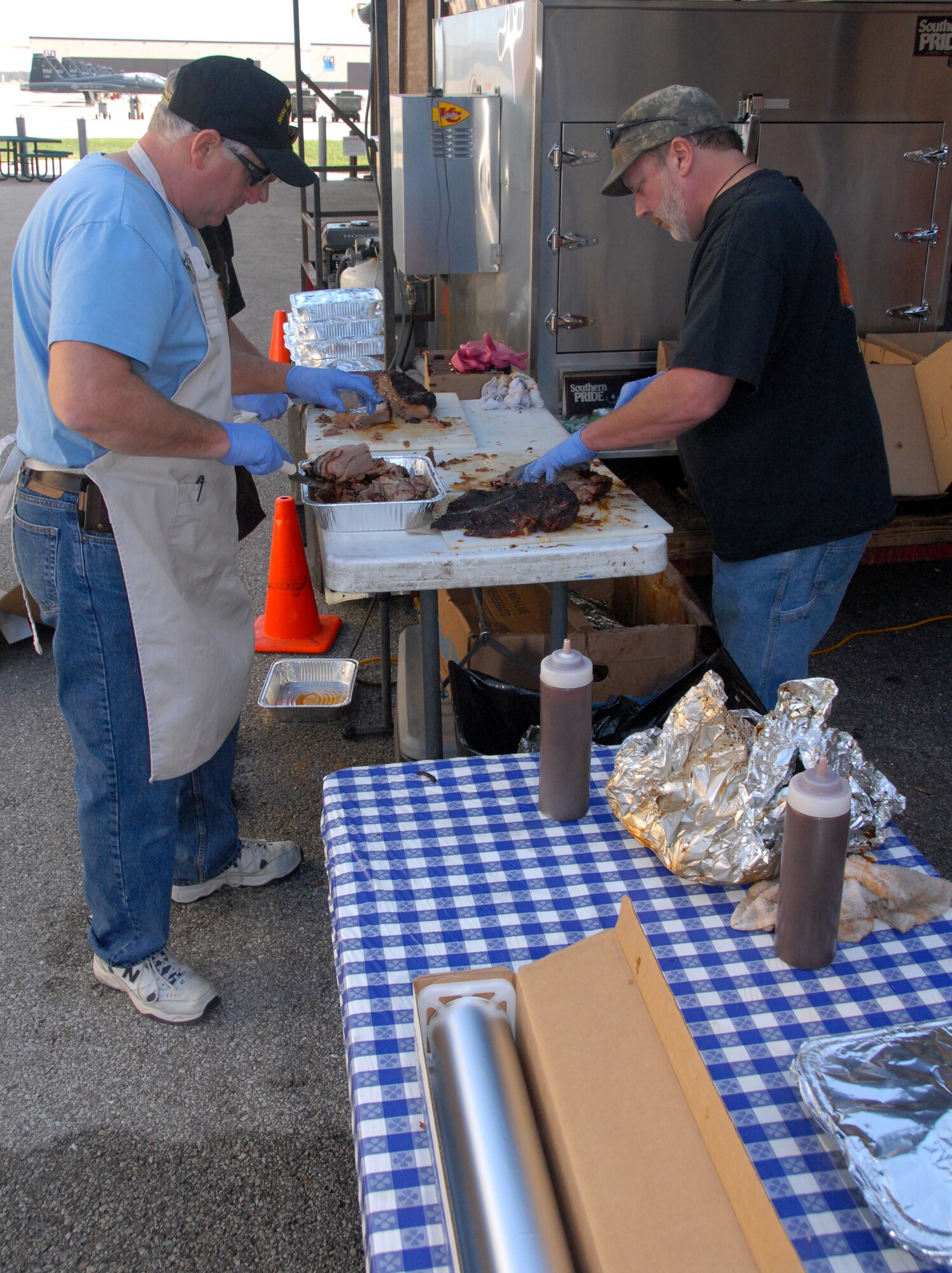 Cousins David and Dean Green prepare barbecued meat for Air Force Reservists from the 442nd Fighter Wing Nov. 7, 2009, at Whiteman Air Force Base, Mo.  The two men are a part of a group of volunteers from Fishnet Security, INC., who volunteer their time and barbecue talents to prepare feasts for American service personnel.  The group has been cooking for more than four years to say "thank you" to military members for their sacrifices and service.  Fishnet Security is a private company based in Kansas City.  The group has cooked barbecue for the Citizen Airmen of the 442nd FW in the past as a way to show appreciation for the wing's contribution to national defense.  (U.S. Air Force photo/Staff Sgt. Kent Kagarise)  