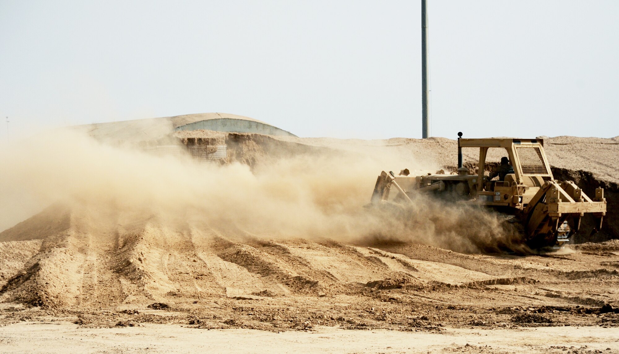 An Airman stockpiles dirt with a bulldozer during construction of a new container repair yard Nov. 2, 2009, at Joint Base Balad, Iraq. By using containers repaired here instead of purchasing new ones, the projected savings total more than $100 million as military assets withdraw from Iraq. The Airman is from the 732nd Expeditionary Civil Engineer Squadron. (U.S. Air Force photo/Senior Airman Christopher Hubenthal) 