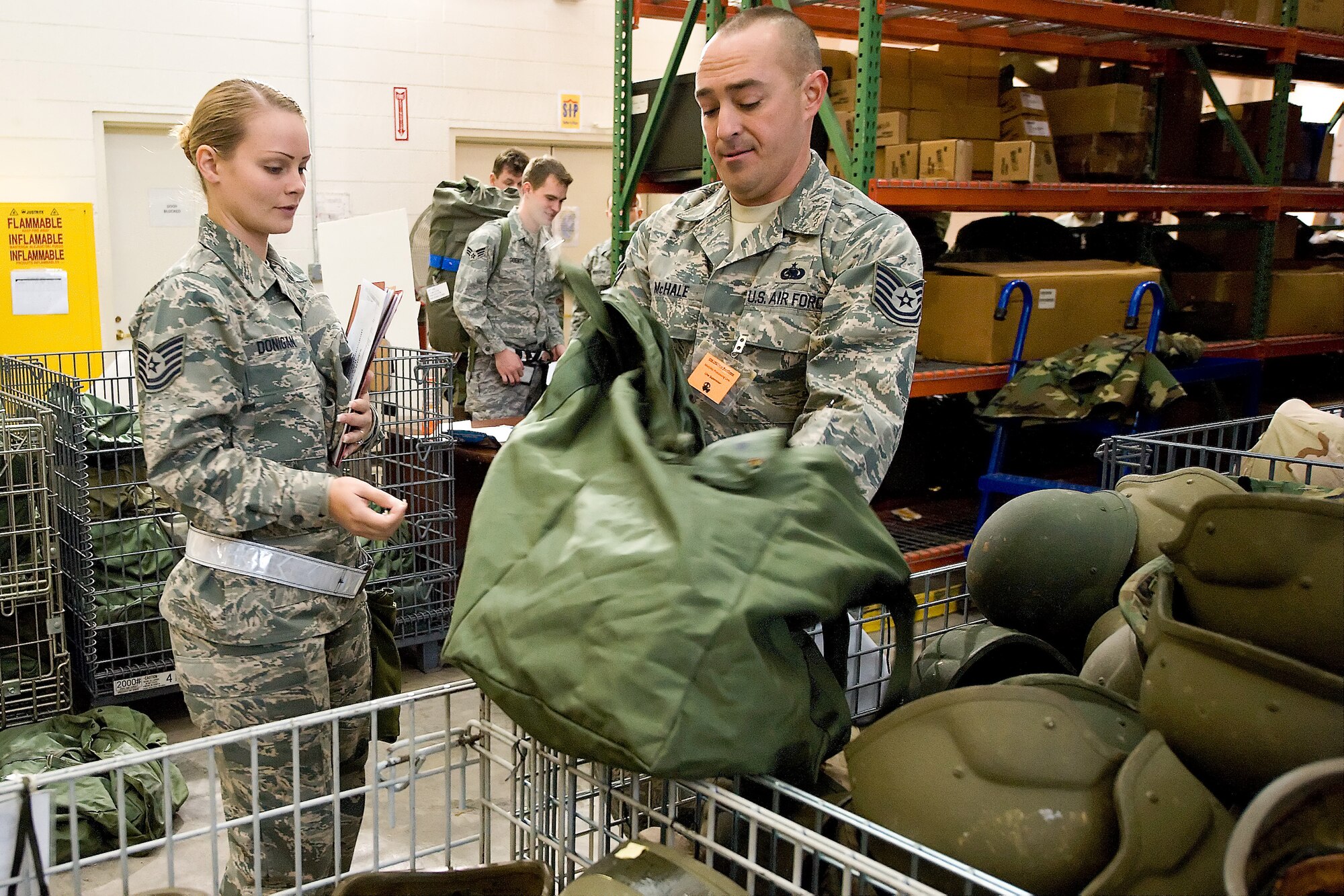 Tech. Sgt. Gerard McHale, 46th Aerial Port Squadron, hands Tech. Sgt. Destiny Donigan, 46th APS, her chemical warfare gear during a base deployment exercise Nov. 7. More than 140 512th Airlift Wing reservists here participated in exercise, which allows base members to practice mobility processes and ensures readiness. (U.S. Air Force photo/Roland Balik)