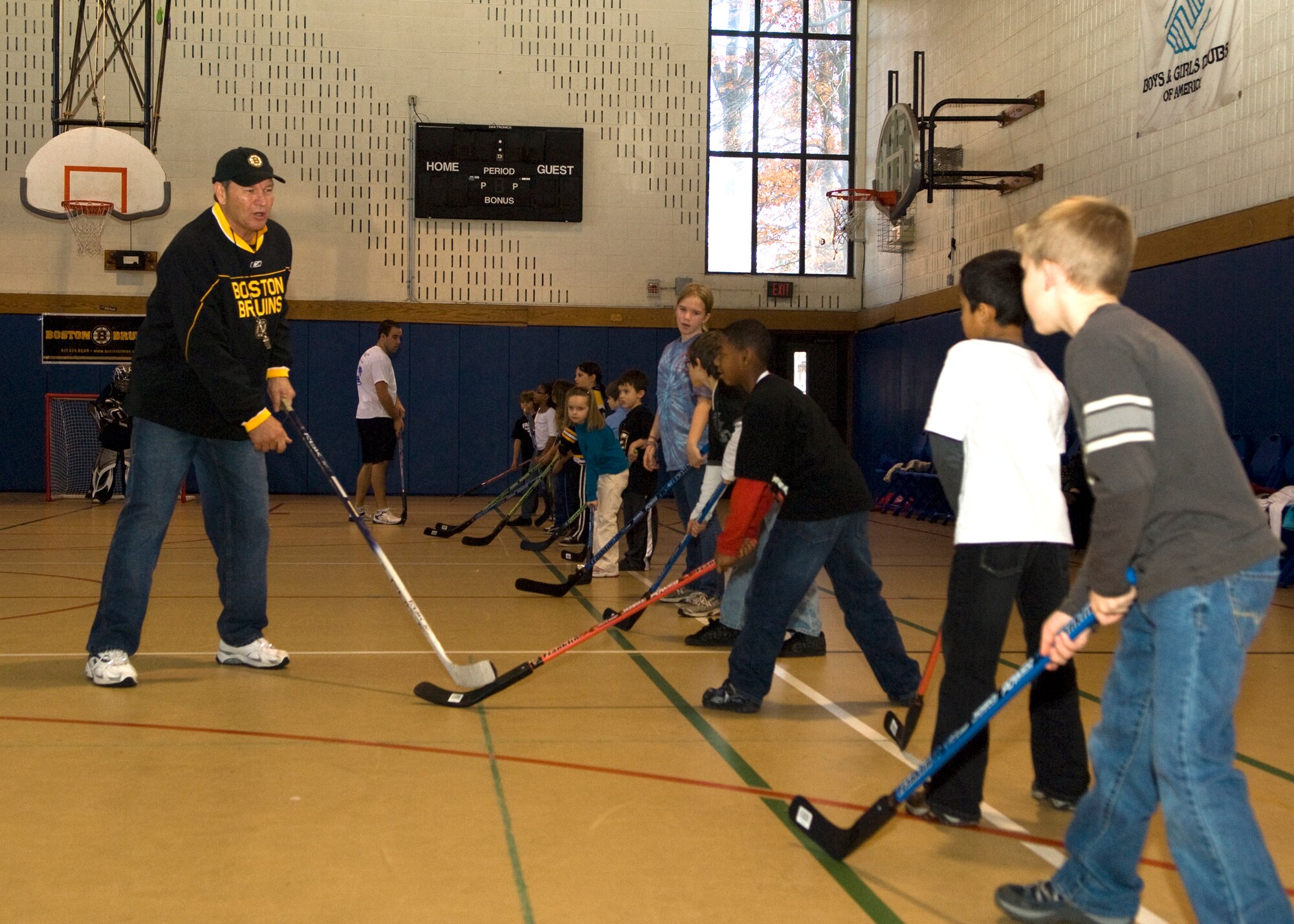 HANSCOM AIR FORCE BASE, Mass. – Boston Bruins alumnus Tommy Songin shows Hanscom children some fundamental stick maneuvers during an Air Force Family Week street hockey event at the Hanscom Youth Center, Nov. 4, sponsored by the Boston Bruins. Bruins staff led Hanscom children through a number of street hockey drills focusing on the fundamentals of play. The Bruins donated all of the street hockey equipment to Hanscom’s Youth Center so children could continue to enjoy the game. (U.S. Air Force photo by Walter Santos)