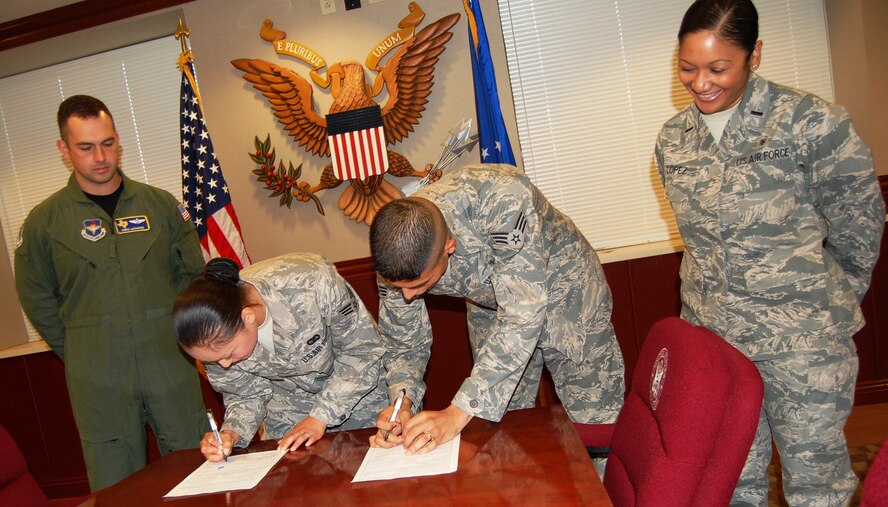 LAUGHLIN AIR FORCE BASE, Texas – Senior Airmen Angeles and Luis Perez each sign reenlistment contracts as Lt. Col. Christopher Lachance and 1st Lt. Vikki Lopez look on as witnesses. The couple, who have been married for four years, reenlisted for their second four-year term in the Air Force. (U.S. Air Force photo by Joel Langton)