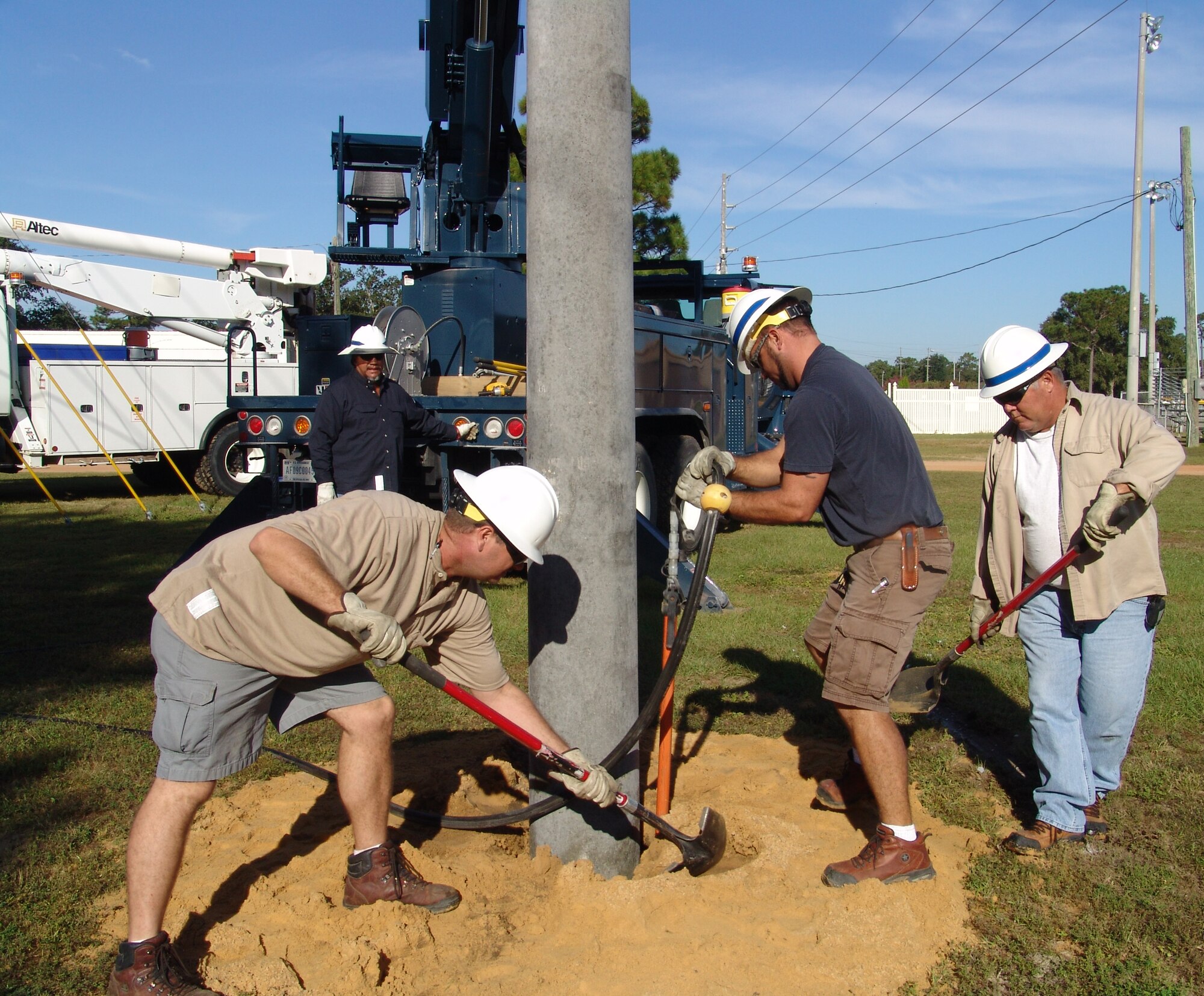 Mike Griswold, Dusty Dees and Tom Dennis set a power pole after Robert Hinojosa used an auger to dig the hole.  It is one of many duties that falls under the 96th Civil Engineer Squadron's exterior electrical shop. (USAF photo/Lois Walsh)