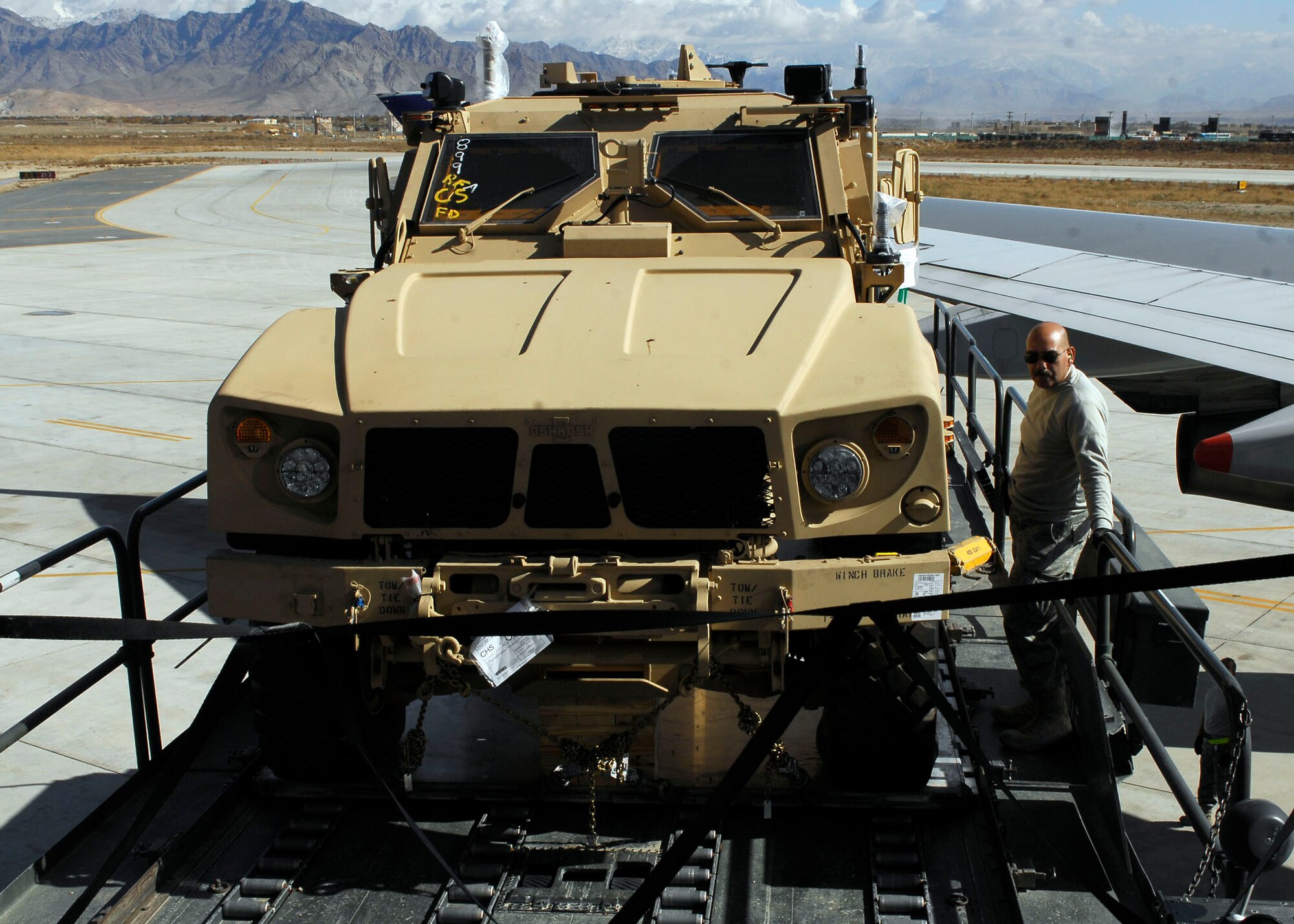BAGRAM AIRFIELD, Afghanistan -- Master Sgt. Andrew Garcia, a ramp section supervisor from the 455th Expeditionary Aerial Port Squadron, stands next to a Multipurpose All Terrain Vehicle making sure it doesn't move while the K-loader lowers it to the ground Nov. 9, 2009.  Sergeant Garcia is deployed from Lackland Air Force Base, Texas and hails from San Antonio.  (U.S. Air Force photo/Senior Airman Felicia Juenke)