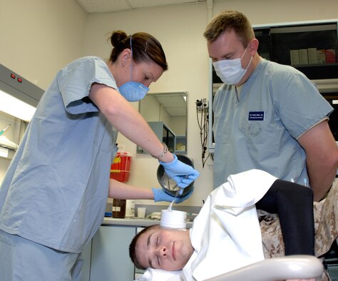 Dental technician Staff Sgt. Dinah Laduke (left), Maxillofacial Prosthodontics Element NCO-in-charge, helps Army Maj. (Dr.) Thomas Gunnell, oral maxillofacial prosthodontics fellow, apply a mold compound to Marine Sgt. Wade Knight's ears. Dr. Gunnel made molds of Sergeant Knight's ears Oct. 27 at the MacKown Dental Clinic, Lackland Air Force Base, Texas. The molds will be used to make prosthetic ears for Marine Capt. Ryan Voltin. Both Captain Voltin and Sergeant Knight were injured in Iraq and met at the Warrior Transition Program, Brooke Army Medical Center, Fort Sam Houston, Texas. Major Gunnel and Sergeant Laduke are assigned to the 59th Dental Training Squadron. (U.S. Air Force photo/Master Sgt. Kimberly A. Yearyean-Siers)