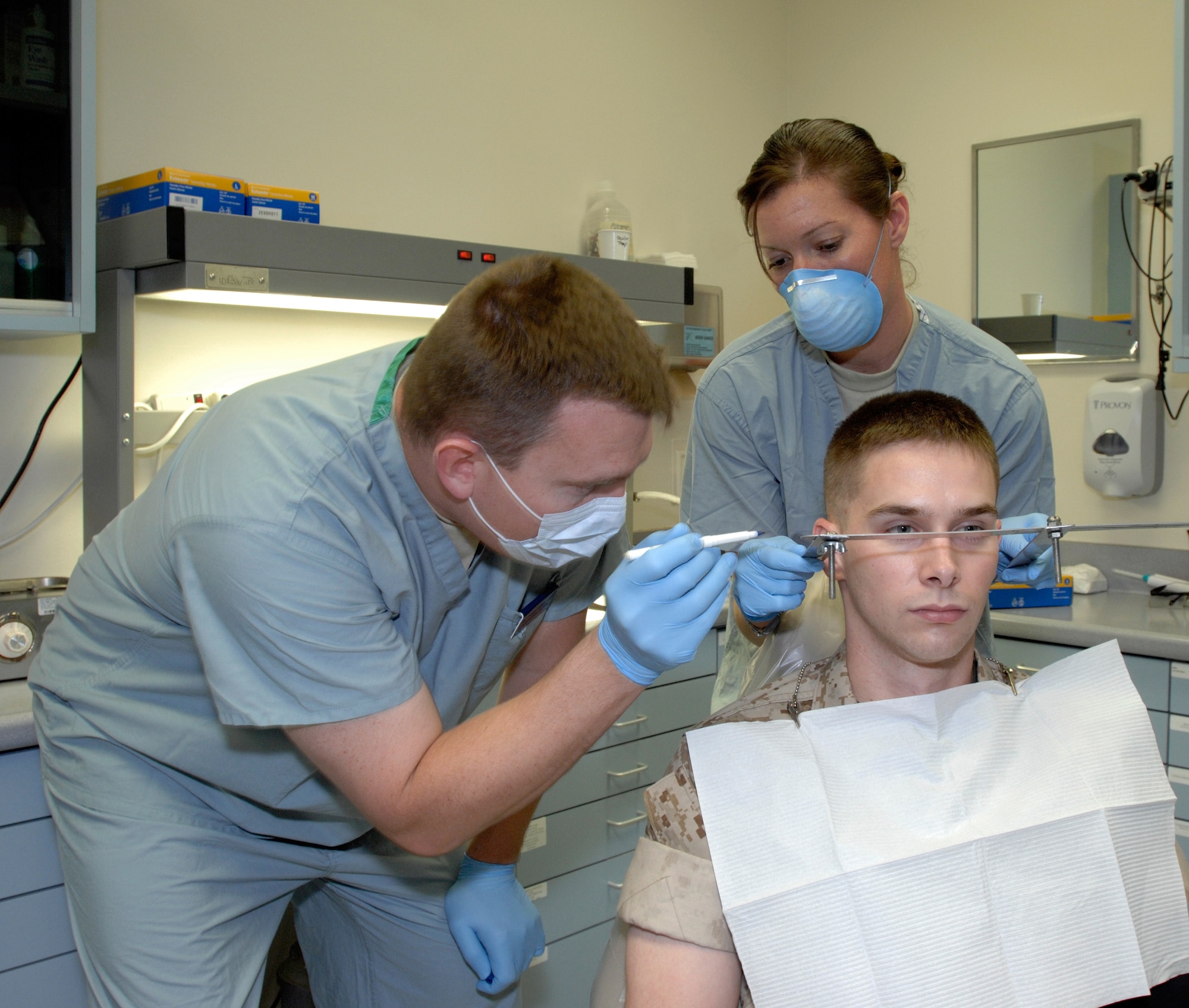 Army Maj. (Dr.) Thomas Gunnell, oral maxillofacial prosthodontics fellow (left), measures the position of Marine Sgt. Wade Knight's ears with the help of dental technician Staff Sgt. Dinah Laduke, NCO-in-charge of the Maxillofacial Prosthodontics Element, Oct. 27 at MacKown Dental Clinic, Lackland Air Force Base, Texas.  Sergeant Knight had molds made of ears as part of a procedure to make prosthetic ears for fellow wounded warrior Marine Capt. Ryan Voltin. Major Gunnell and Sergeant Laduke are assigned to the 59th Dental Training Squadron. (U.S. Air Force photo/Master Sgt. Kimberly A. Yearyean-Siers)
