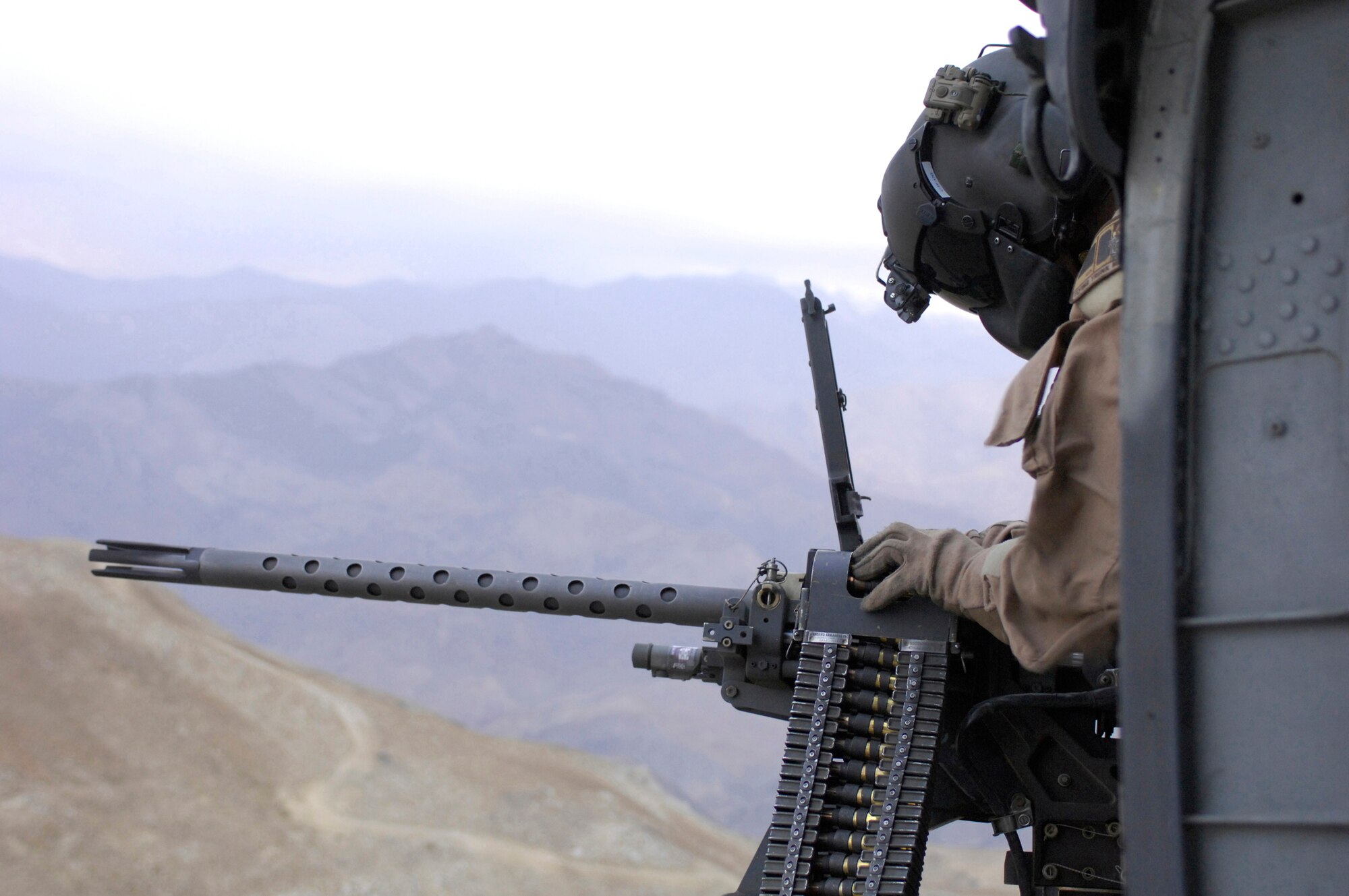 Staff Sgt. Justin Schramm leans out to check the M2 .50 caliber machine gun mounted on an HH-60G Pave Hawk while flying in Afghanistan. Sergeant Schramm is currently stationed at Kadena Air Base, Japan and is originally from Eugene, Ore. (U.S. Air Force photo/Senior Airman Susan Tracy)