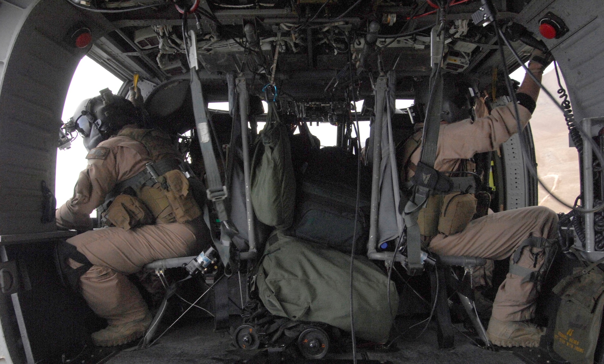 Aerial gunner Staff Sgt. Justin Schramm (left), and flight engineer Senior Airman Michael Price (right), watch the ground while patroling the skies in Afghanistan in an HH-60G Pave Hawk. Sergeant Schramm and Airman Price are both deployed from Kadena Air Base, Japan; Sergeant Schramm is from Eugene, Ore., originally and Airman Price is from Tuscaloosa, Ala. (U.S. Air Force photo/Senior Airman Susan Tracy)