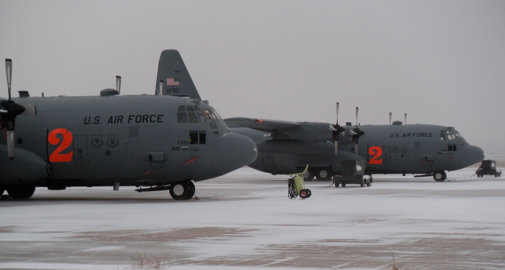 Two Air Force Reserve C-130H3s, assigned to the 302nd Airlift Wing, brave Colorado's first major winter storm Oct. 29 at Peterson Air Force Base, Colo. Maintenance personnel work to prepare aircraft for missions by de-icing its wings and surface areas, while Colorado Springs Airport officials plow snow-covered taxiway and runway surfaces to allow the aircraft to take off. (U.S. Air Force photo/Staff Sgt. Stephen J. Collier)