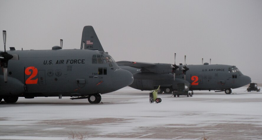 Two Air Force Reserve C-130H3s, assigned to the 302nd Airlift Wing, brave Colorado's first major winter storm Oct. 29 at Peterson Air Force Base, Colo. Maintenance personnel work to prepare aircraft for missions by de-icing its wings and surface areas, while Colorado Springs Airport officials plow snow-covered taxiway and runway surfaces to allow the aircraft to take off. (U.S. Air Force photo/Staff Sgt. Stephen J. Collier)