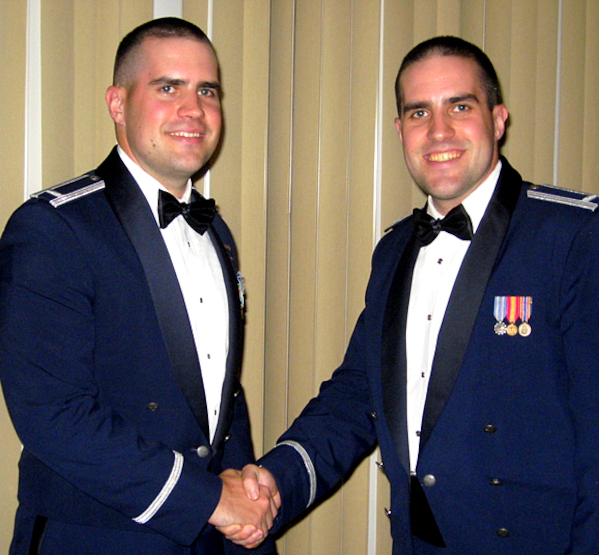 First Lt. Jared Scherff, left, gives his twin brother, 1st Lt. Andrew Scherff, the second half of a set of broken wings during Jared's graduation dinner, Oct. 2. At every undergraduate pilot training graduation, the Air Force issues each new pilot a first pair of wings. Tradition requires that the pilot never wear that first pair. Instead, for good luck, the wings should be broken in two parts -- one half for the pilot and the other for a close friend or relative. Andrew gave his brother the other half of his broken wings when Jared returned from SERE (Survival, Evasion, Resistance and Escape) training Nov. 7. (Courtesy photo)

