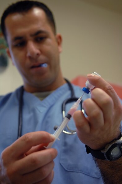 Staff Sgt. Eduardo Quezada, Army veterinarian technician, fills a syringe with a rabies vaccination prior to administering it to a family pet here Nov 10.  The clinic aids servicemembers in keeping pets legal, safe and healthy.  (U.S. Air Force Photo/ Senior Airman Jessica Mae Snow) (Released)
