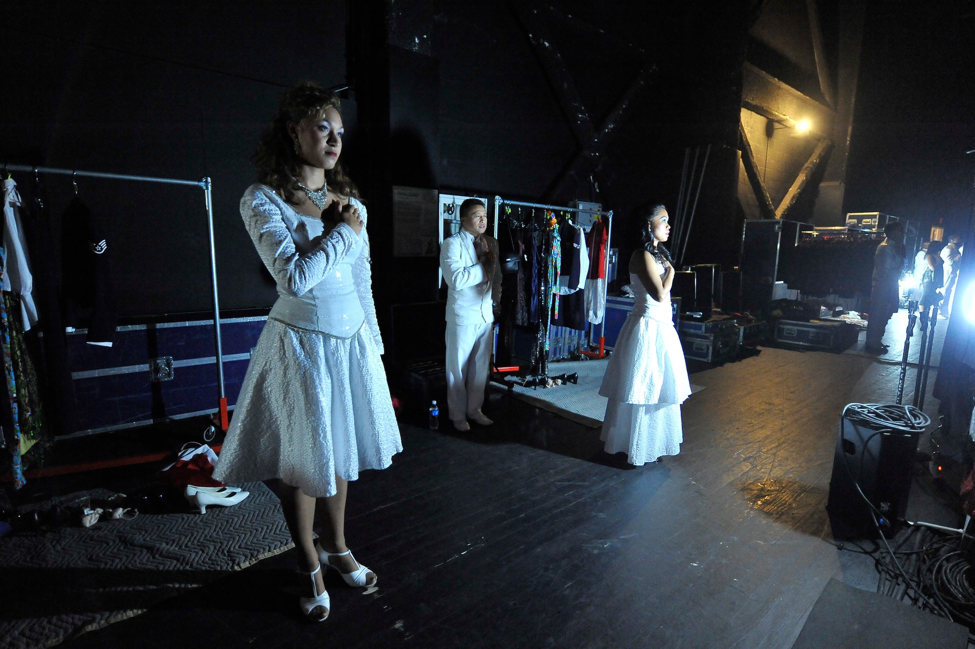 First Lt. Angela Waterworth, left, Senior Airman Cristy Henderson and Master Sgt. Herbert Ancog show their respect during the national anthem while back stage during the Tops in Blue "To Dream" show at the North Charleston Performing Arts Center in North Charleston Nov. 8. Since its first world tour in 1953, Tops in Blue has performed on film, produced albums and appeared on national television with legends Ed Sullivan, Bob Hope and many others. Lieutenant Waterworth, Sergeant Ancog and Airman Henderson are performers with Tops in Blue. (U.S. Air Force photo/James Bowman)