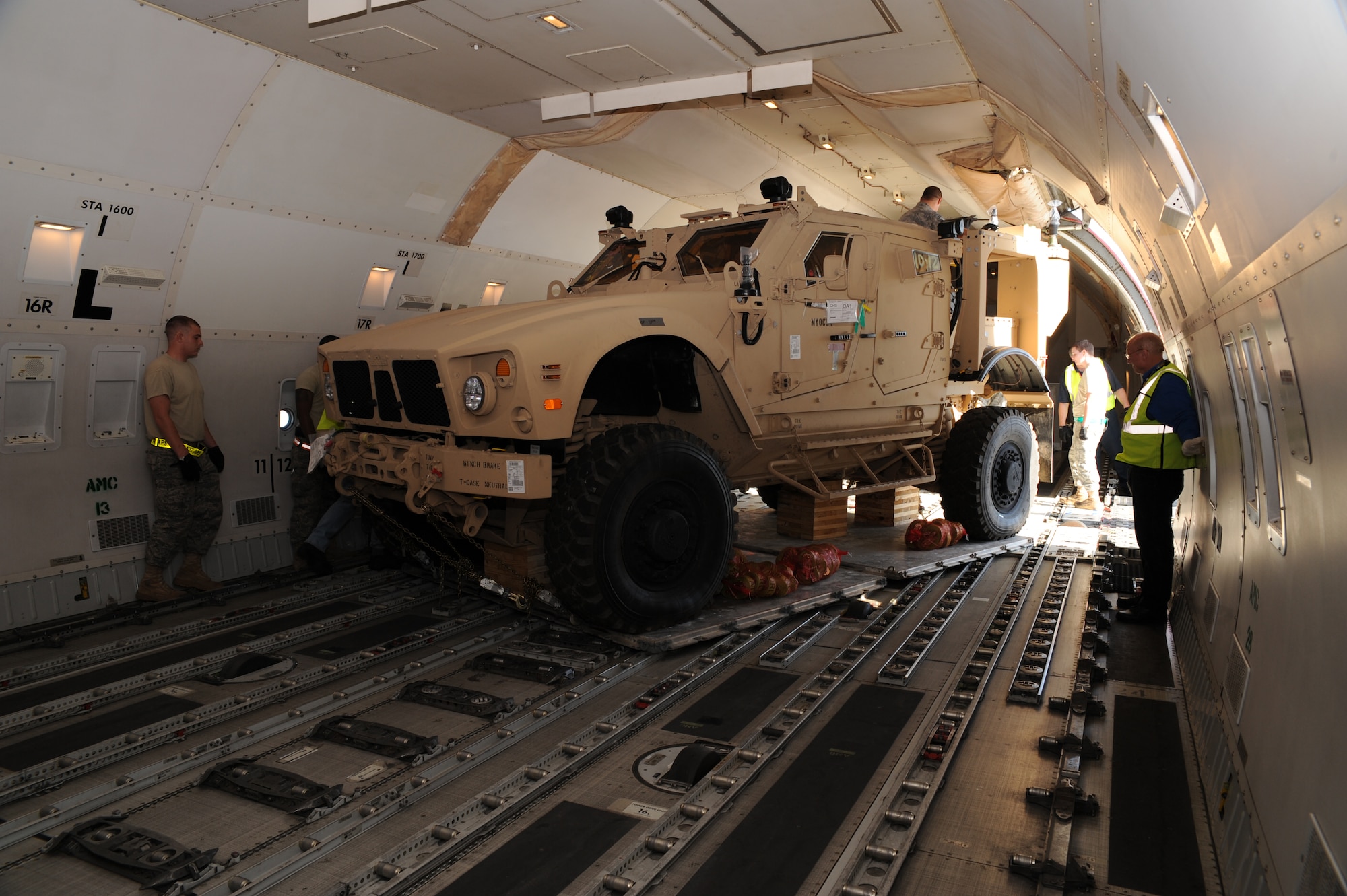 Airmen with the 437th Aerial Port Squadron and ground operations crew members with Atlas Air watch as a mine-resistant, ambush-protected all-terrain vehicle is loaded onto a Boeing 747-400 aircraft here Nov. 7. The 437 APS air transportation specialists fit five M-ATVs on the civilian aircraft during the first-ever load aboard a 747-400. (U.S. Air Force photo/Staff Sgt. Marie Brown)