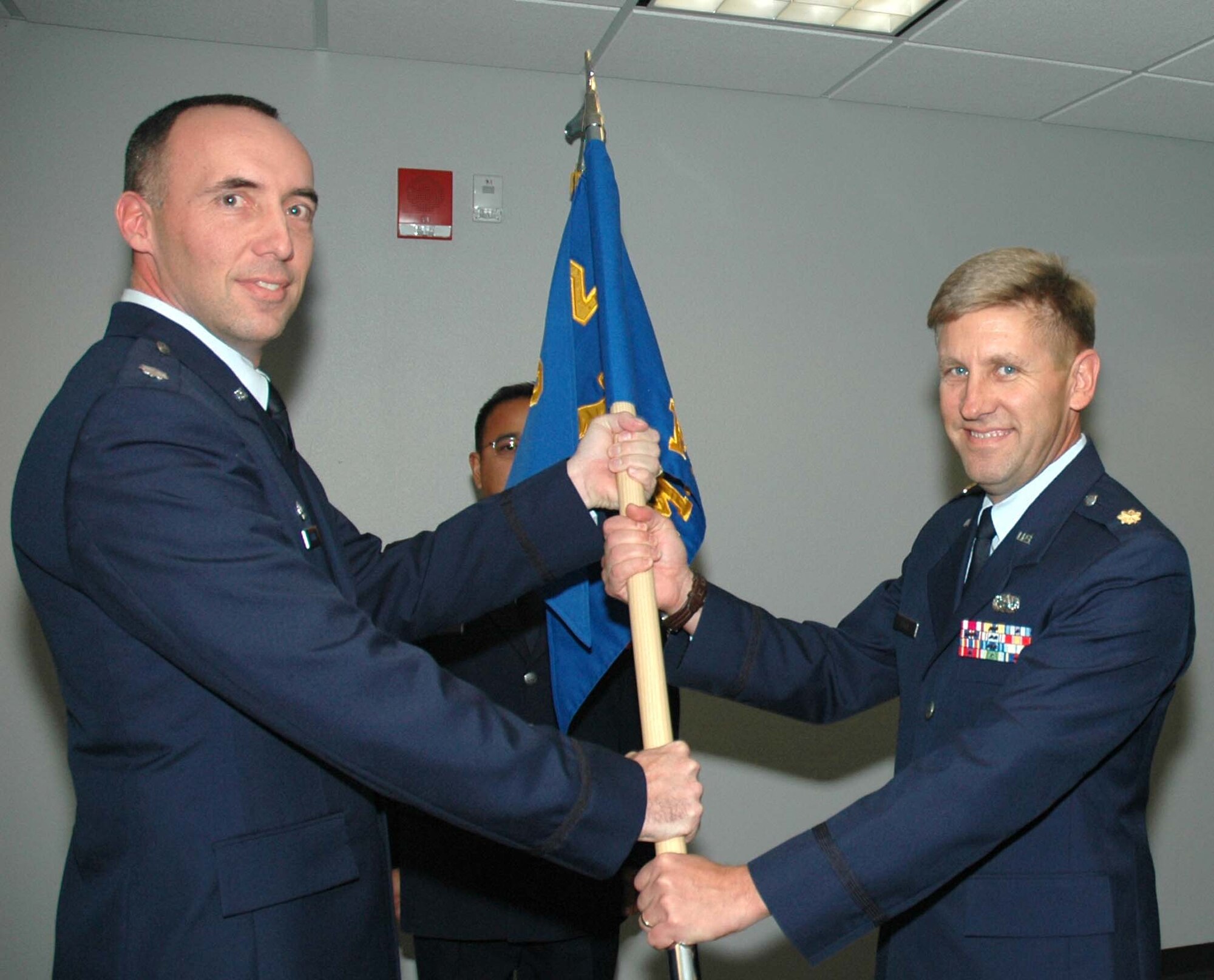 Maj. Alan Flolo (right) accepts the 302nd Mission Support Flight guidon from Lt. Col. Michael Burns (left) Nov. 8 during a change of command ceremony at Peterson Air Force Base, Colo. Major Flolo accepted command of the flight from its outgoing commander, Maj. Joe Colunga, after serving as the 302nd Airlift Wing's executive officer. Major Colunga is transferring to the 302nd Maintenance Group. Colonel Burns is the commander of the 302nd Mission Support Group. (U.S. Air Force photo/Tech. Sgt. Daniel Butterfield)