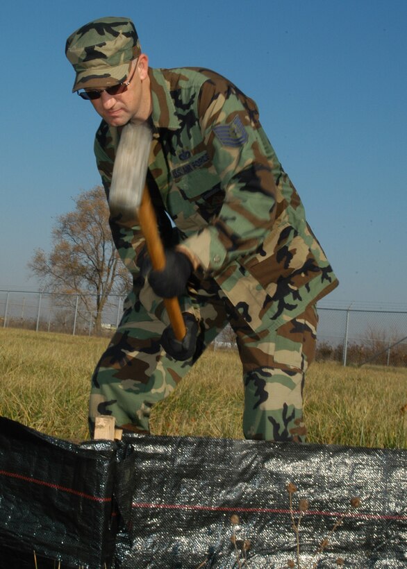 GRISSOM AIR RESERVE BASE, Ind. -- Tech Sgt. Jeff Engel, a heavy equipment operator with the 434th Civil Engineer Squadron, pounds a stake into the ground with a sledge hammer at a new training site for civil engineers just west of State Road 31.  The site will allow Airmen to practice using the equipment in a safe environment.  The barricade being built will stop debris from falling into the protected wet land areas during construction and use. (Air Force photo/ Staff Sgt. Ben Mota)                                                             