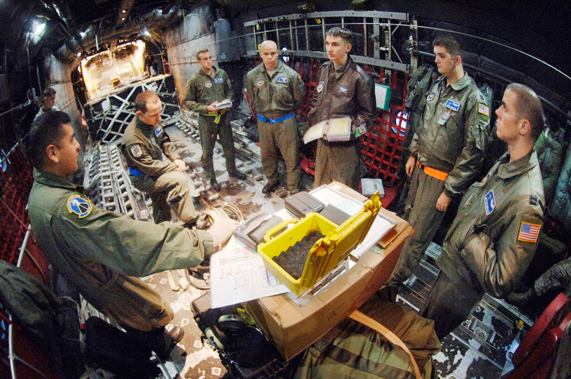 Capt. Tyler Robertson (in a leather jacket) leads a mission brief for (right to left) Capt. Matthieu Rigollet, Capt. Ryan Donohoe, Staff Sgt. Eric Kleser, Capt. Matt Schoomaker, Staff Sgt. Josh Woolridge and Staff Sgt. Victor Reynosa discuss their C-130 Hercules mission Nov. 2, 2009. The aircraft was transferred to the Polish air force's 14th Airlift Squadron at Powidz Air Base, Poland, as part of a program for building partnership capacities between the United States and its allies. Captain Robertson is an aircraft commander, Captain Rigollet is a mission navigator, Captain Donohoe is an instructor navigator, Sergeant Kleser is a flight engineer, Captain Schoomaker is a co-pilot, and Sergeants Woolridge and Reynosa are loadmasters. (Defense Department photo/Master Sgt. Scott Wagers)