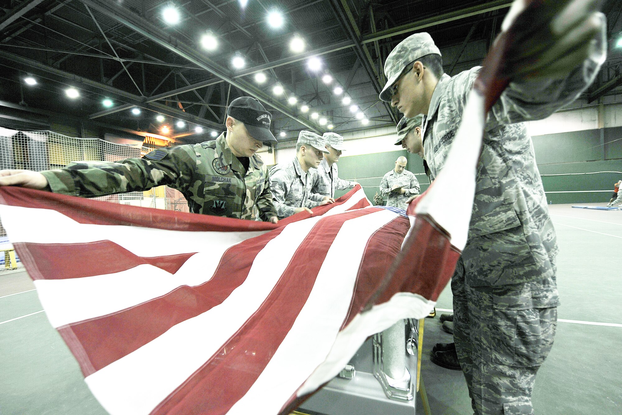 Senior Airman Noel Sweeney evaluates honor guard members as they drape an American flag across a casket during a training session Oct. 21, 2009, at Offutt Air Force Base, Neb. Air Force Honor Guard trainers visited the base to evaluate and help sharpen the skills of base honor guard members. Airman Sweeney is an Air Force Honor Guard member. (U.S. Air Force photo/Charles Haymond) 
