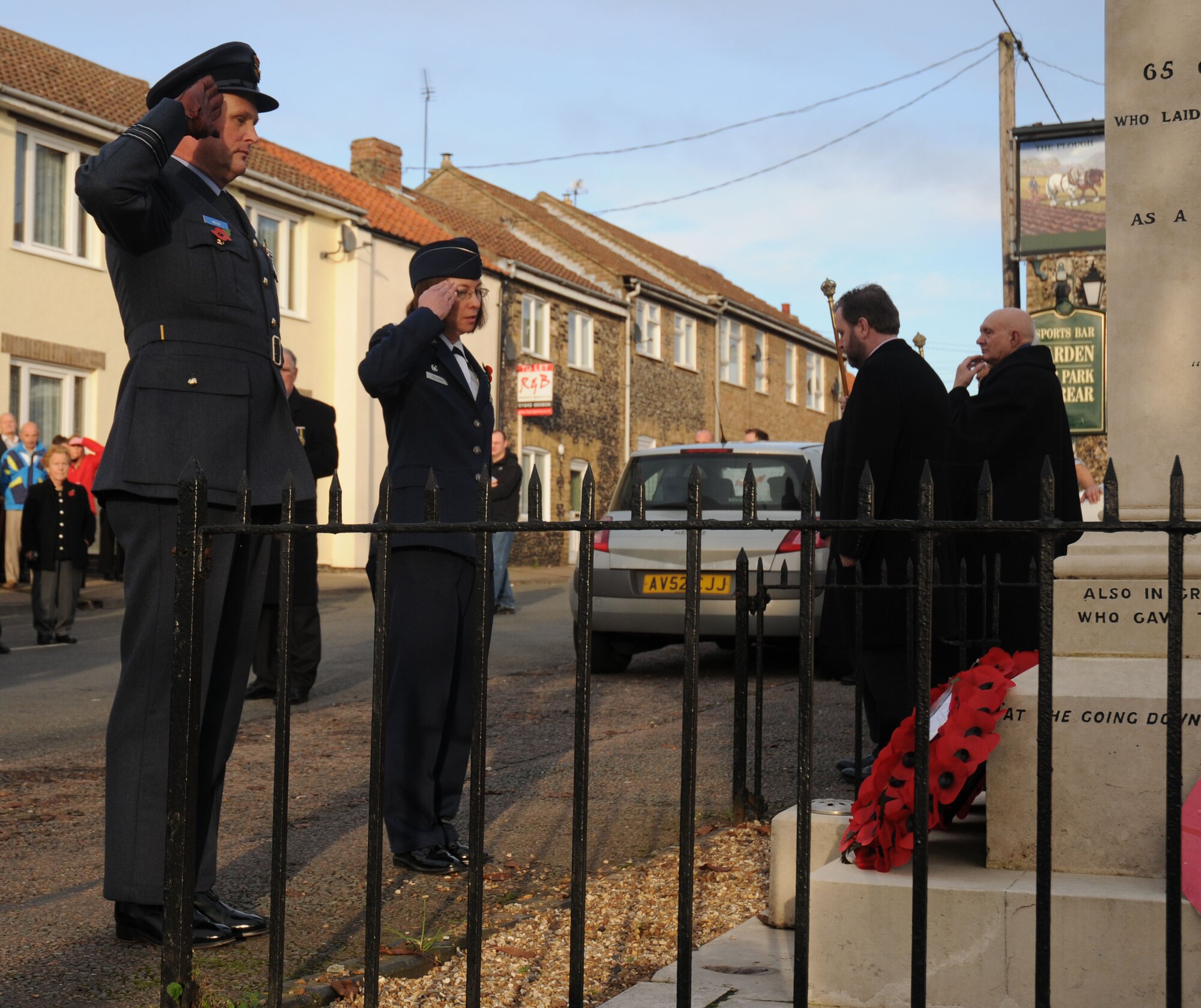 Sqdn. Ldr Jerry Neild, RAF commander, and Lt. Col. Annata Sullivan, 48th Inpatient Squadron commander, salute after laying poppy wreaths on the Lakenheath War Memorial during a Remembrance Sunday memorial service Nov. 8. In the U.K., wearing red poppies and laying poppy wreaths at memorial sites is a way to honor those who lost their lives or were injured during war. (U.S. Air Force photo by Staff Sgt. Megan Lyon)