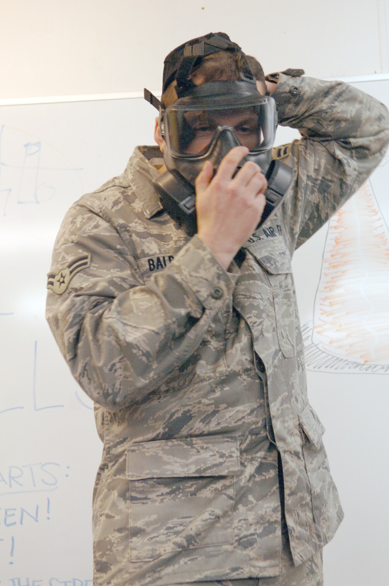 U.S. Air Force Airman 1st Class Michael Balbaugh, 886th Civil Engineer Squadron readiness and emergency management apprentice, demonstrates how to put on the M-50 Joint Service General Purpose Mask, Nov. 5, 2009, Ramstein Air Base, Germany. The mask has a redesigned head harness that allows for a better seal around the face.  (U.S. Air Force photo by Senior Airman Amanda Dick)
