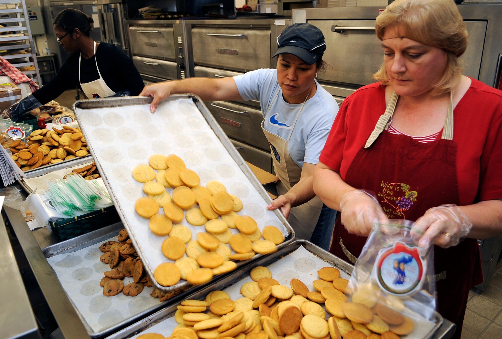 Elsa Wong, left, replenished a tray of sugar cookies as Karen Forster fills bags with cookies at Osan Air Base, Republic of Korea, during the annual "Cookie Crunch".  The Cookie Crunch program is hosted by the Osan Officer's Spouses Club and base leadership to bring a taste of home to all Airmen, Soldiers, Sailors, Marines and Korean Airmen on the peninsula. (U.S. Air Force photo/Staff Sgt. Brian Ferguson)





