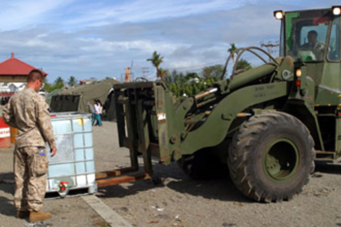 Marine Capt. James R. Stover of the 15th Marine Expeditionary Unit (Special Operations Capable) directs a forklift as it unloads crates of fresh water at a local mosque that is temporarily being used as a refugee shelter.