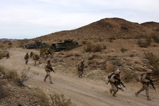 Marines with Company G, 2nd Battalion, 7th Marine Regiment, rush to get into position to fend off a mock ambush at the Combat Center's Range 205 Nov. 11. The Marines were attacked by notional artillery rounds and mock improvised explosive devices.
