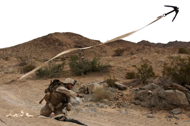 Lance Cpl. Michael Cheatham, a rifleman with Company G, 2nd Battalion, 7th Marine Regiment, hurls a grappling hook to clear concertina wire from the roadway to allow fellow Marines to push forward against the notional enemies at Combat Center's Range 205 Nov. 11. Co. G was chosen as the mechanized company for the battalion's upcoming deployment with the 31st Marine Expeditionary Unit and completed the last of their pre-deployment training Wednesday night.