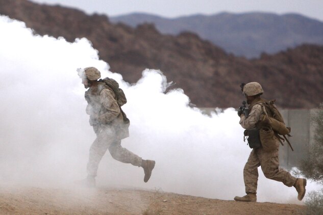 Marines with Company G, 2nd Battalion, 7th Marine Regiment, rush through smoke and into buildings at the Combat Center's Range 205 Nov. 11 to clear notional targets and ensure their skills in Military Operations in Urban Terrain do not atrophy with disuse. Co. G is slated to deploy with the 31st Marine Expeditionary Unit in January and will be the battalion's mechanized company.