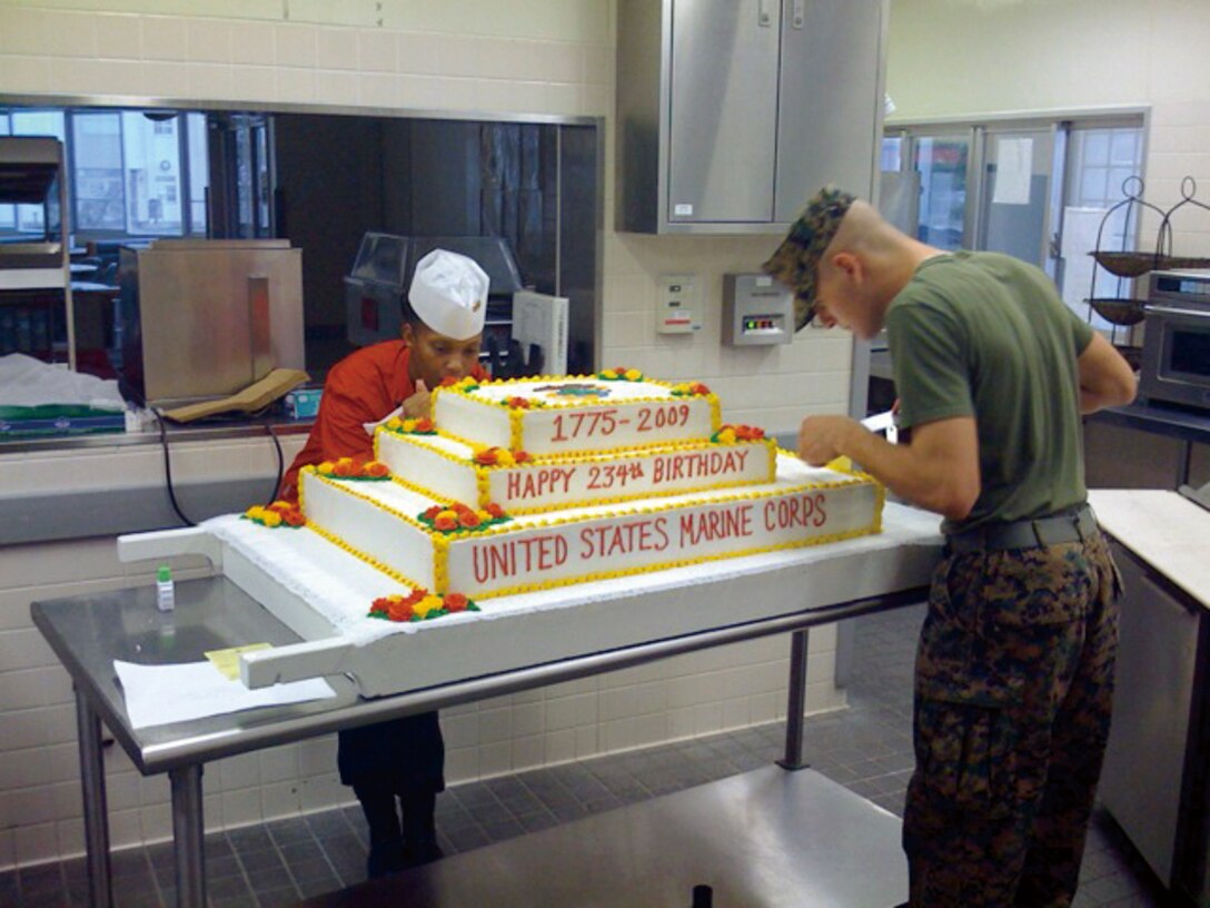 Staff Sgt. Latisha S. Franklin, the battalion mess chief for Headquarters Battalion, 3rd Marine Division, III Marine Expeditionary Force, and Cpl. Allan Baer, a cook at the Courtney mess hall, decorate a cake for the Marine Corps birthday last November.