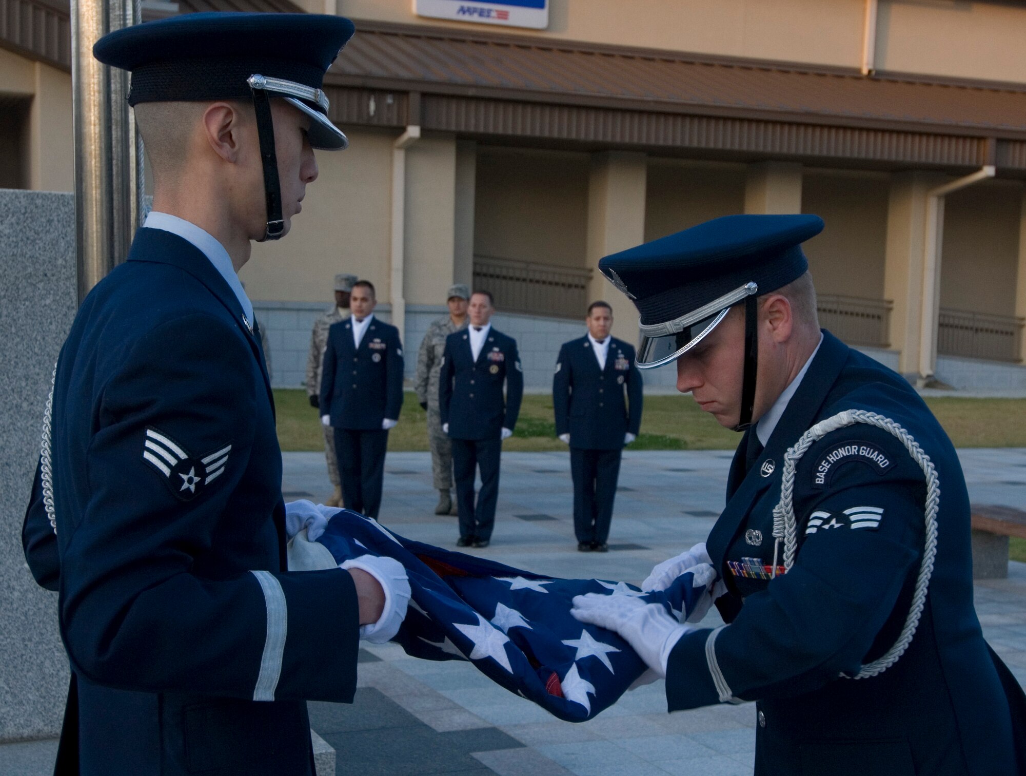 KUNSAN AIR BASE, Republic of Korea -- Senior Airmen Chi Xing, 8th Medical Operation Squadron, and Jeremy Merritt, 8th Maintenance Squadron, fold the American flag during the Veterans Day retreat, here Nov. 11. Both Airmen are part of the Kunsan Air Base Honor Guard, which had a Stand for Freedom fundraisor for Veterans Day. The event started at reveille and ended at retreat. The Stand for Freedom event raised more than $1,900, to help the Honor Guard with incentive programs, trips and uniforms. (U.S. Air Force photo/Senior Airman Roy Lynch)