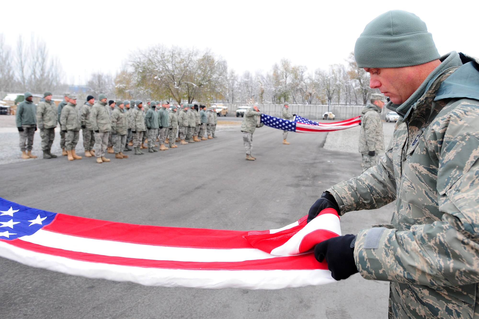 TRANSIT CENTER AT MANAS, Kyrgyzstan -- Senior Master Sgt. James Pittman, 376th Expeditionary Operations Group superintendent, and fellow Airmen fold the colors in honor of fallen N.Y. Fire Chief Peter Ganci Jr. and all those who lost their lives during the terrorist attacks of 9/11. (U.S. Air Force photo/Senior Airman Steele C. G. Britton)