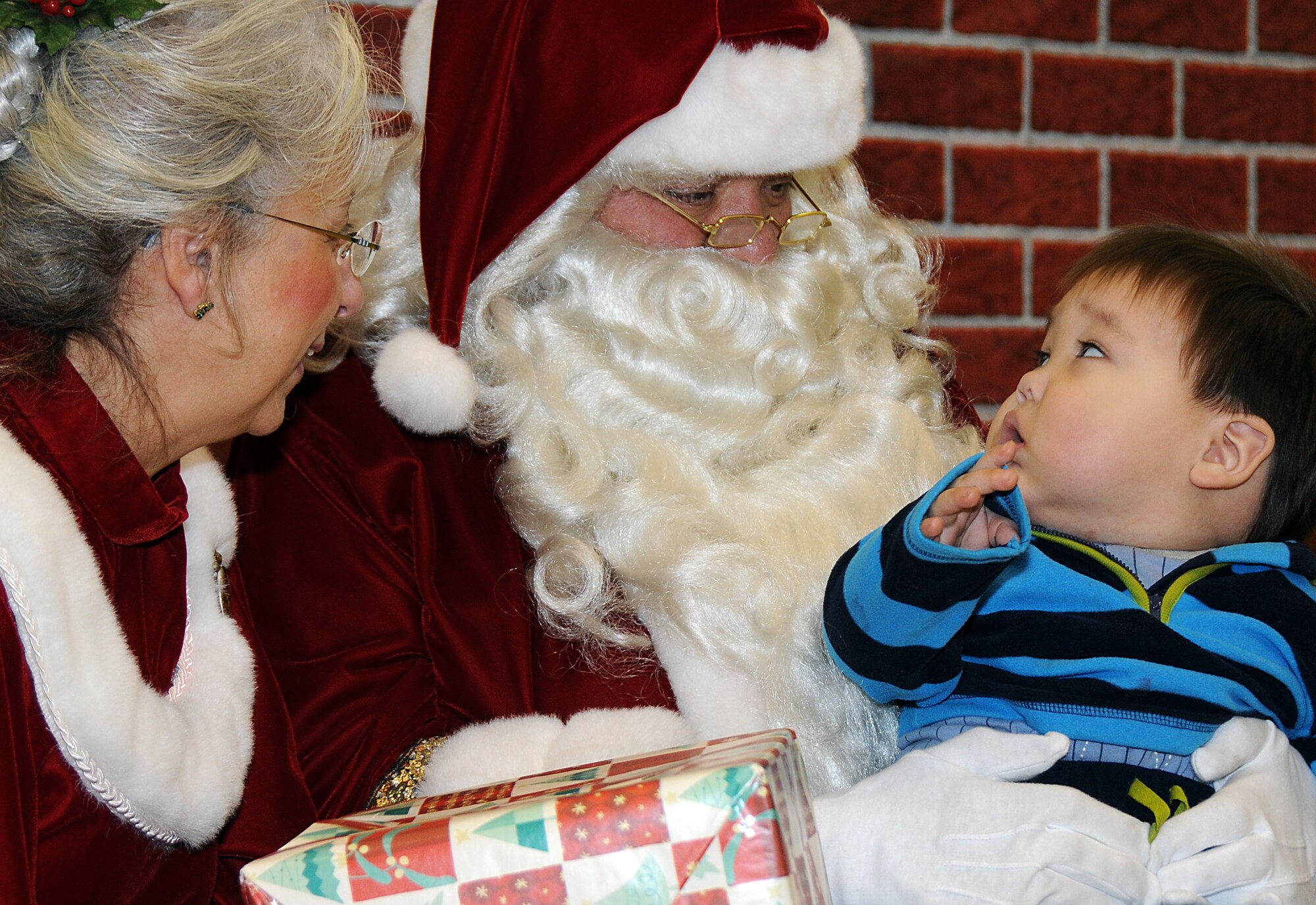 St. George resident Till Lekanof, age 1, gets some personal attention from Santa and Mrs. Santa during an Operation Santa Claus mission on Nov. 7, 2009. U.S. Air Force photo by 1st Lt. John Callahan.