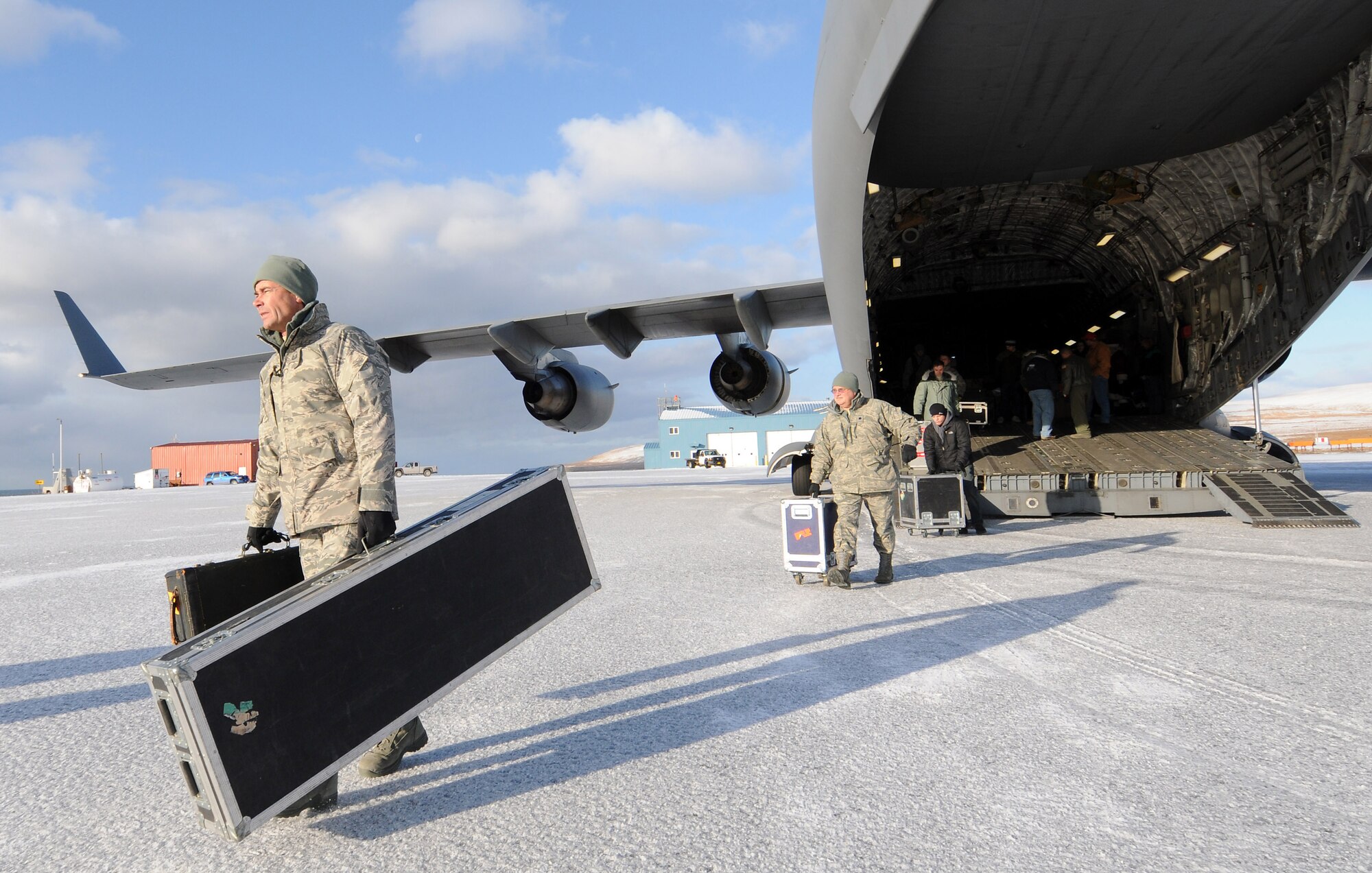MSgt. Ron Larsen, a pianist with the Elmendorf-based Air Force Band of the Pacific, hauls gear off the C-17 that transported the band members and Operation Santa Claus volunteers to St. George. Assisting him as roadie is Lt. Col. Richard Cavens, wing chaplain for the Alaska Air National Guard's 176th Wing. U.S. Air Force photo by 1st Lt. John Callahan.