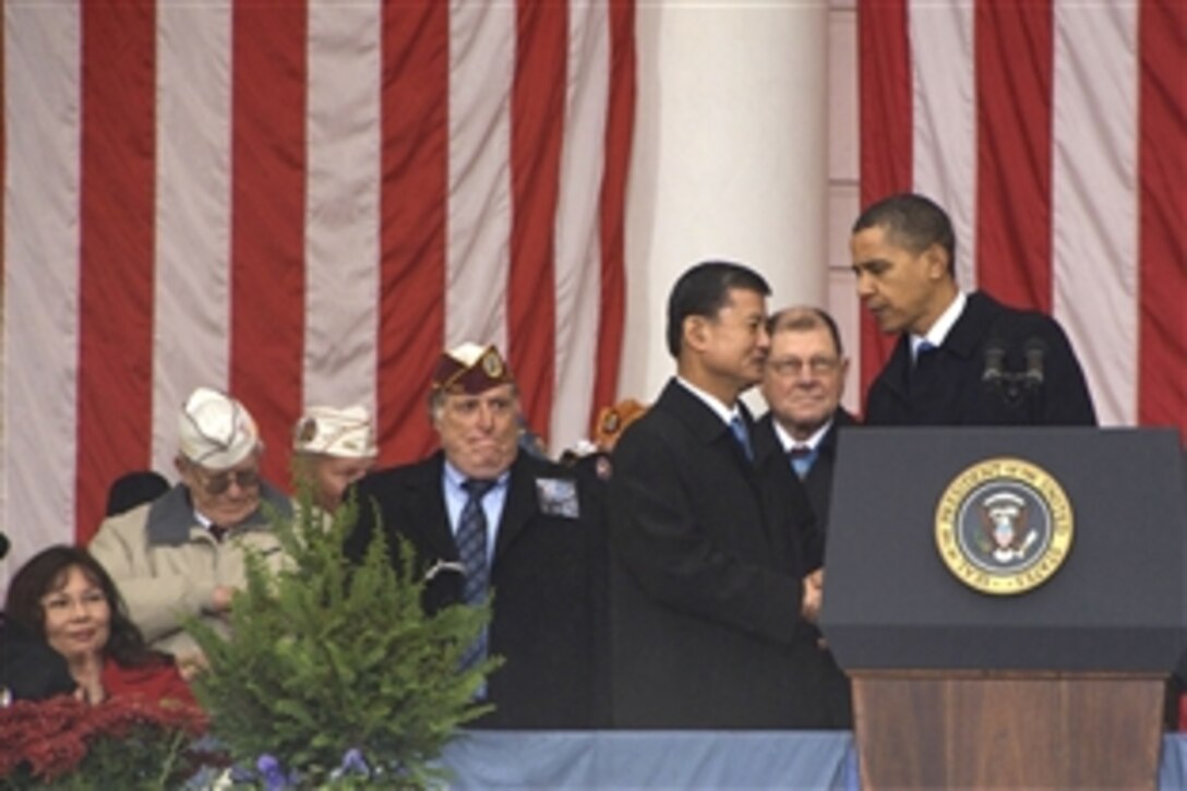 President Barack Obama shakes hands with Veterans Affairs Secretary Eric K. Shinseki as he descends the podium after speaking during Veterans Day services at Arlington National Cemetery, Arlington, Va., Nov. 11, 2009. At the far left is Maj. L. Tammy Duckworth, an Army National Guard helicopter pilot and the Veterans Affairs Department’s assistant secretary for public and intergovernmental affairs.