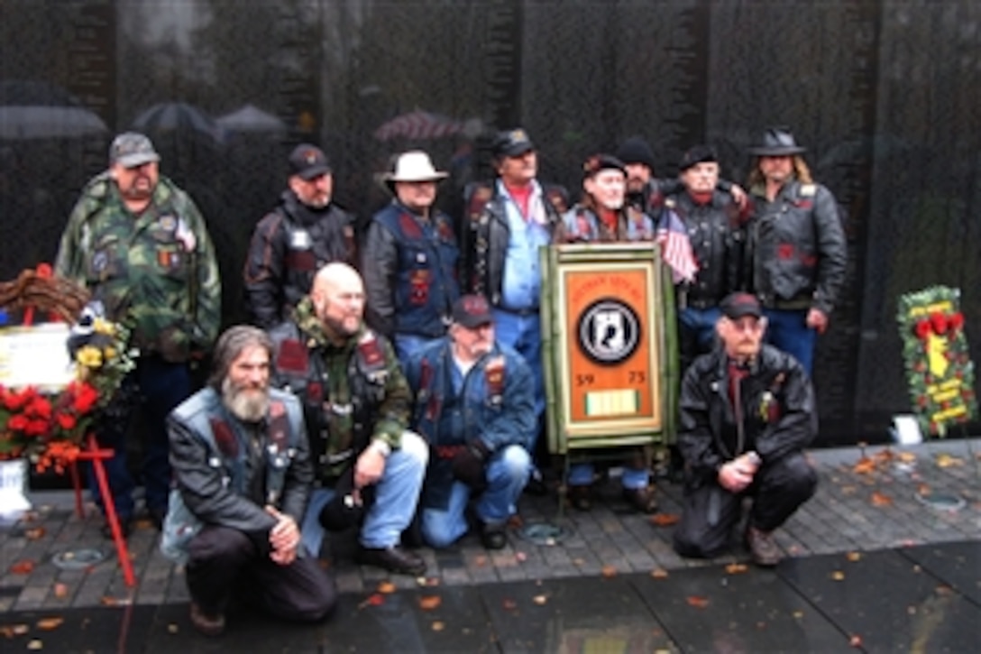 Visitors to the Vietnam Veteran’s Memorial Wall stand beside a plaque commemorating Prisoners of War and Missing in Action on Veterans Day Nov. 11, 2009. Showing in the background are some of the more than 58,000 names of fallen troops etched into the granite partitions of the monument in Washington, D.C.
