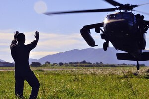 ILOPANGO, El Salvador -- A Salvadoran air force member directs a Joint Task Force-Bravo UH-60 Blackhawk, based out of Soto Cano Air Base, Honduras, to land in order for volunteers to upload food onto it Nov. 12 here. The JTF-Bravo members helped distribute more than 21,000 pounds of food, water, clothing and other hygiene products to villages of El Salvador that have been cut off by mudslides. The towns most affected by the Nov. 8 flooding were Verapaz, Guadalupe, Santa Maria Ostumas and San Vicente. These villages were completely cut off by damaged roads and bridges (U.S. Air Force photo/Staff Sgt. Chad Thompson).