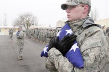 At the Transit Center at Manas, Kyrgyzstan, Senior Airman Zachary Merryman holds the American flag tightly at a ceremony honoring those who've made the ultimate sacrifice since the terrorist attacks of 9/11. Airman Merryman is a radiology technician with the 376th Expeditionary Medical Group. (U.S. Air Force photo/Senior Airman Steele Britton)